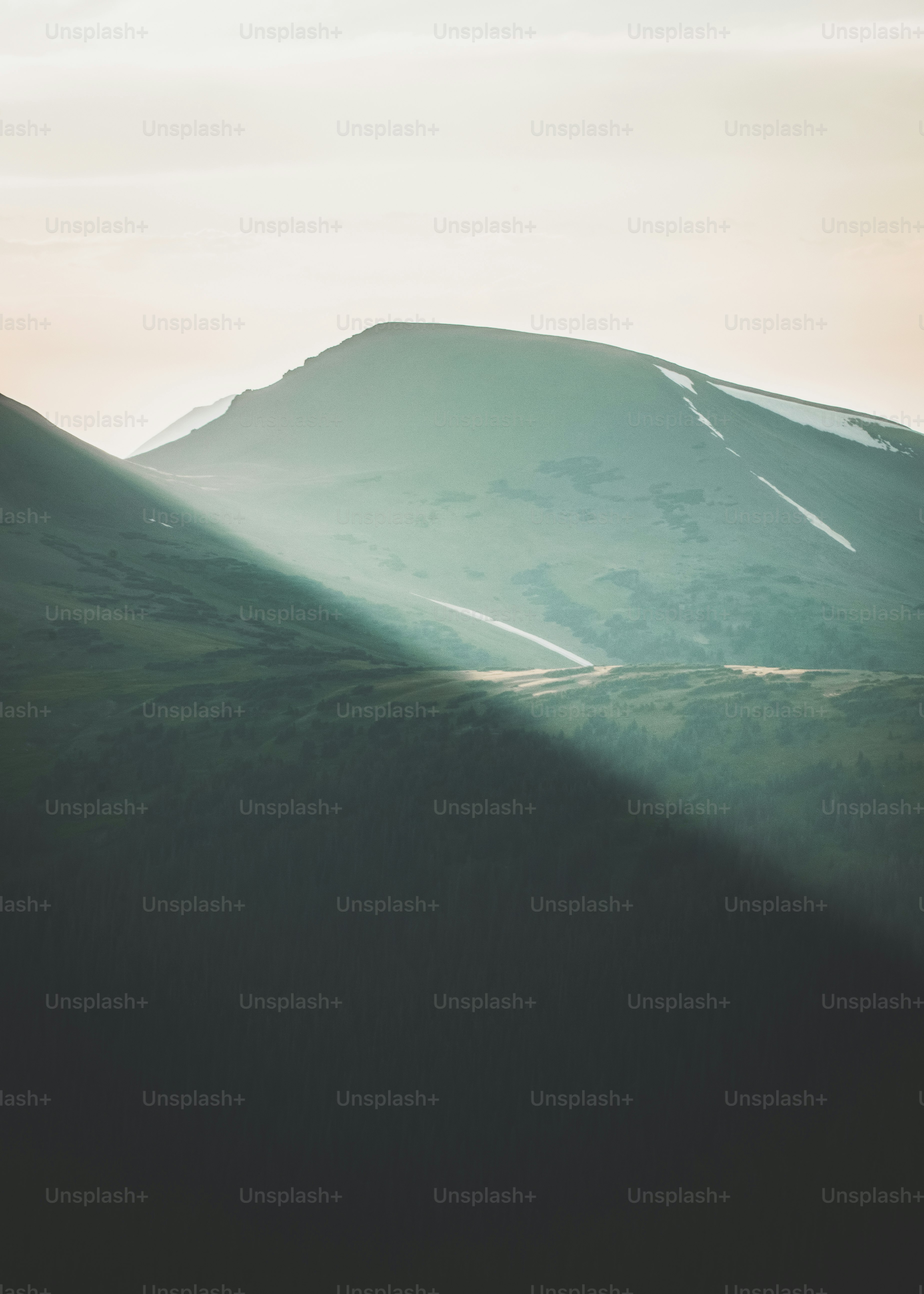 Sunbeams illuminate a majestic mountain range at dawn.