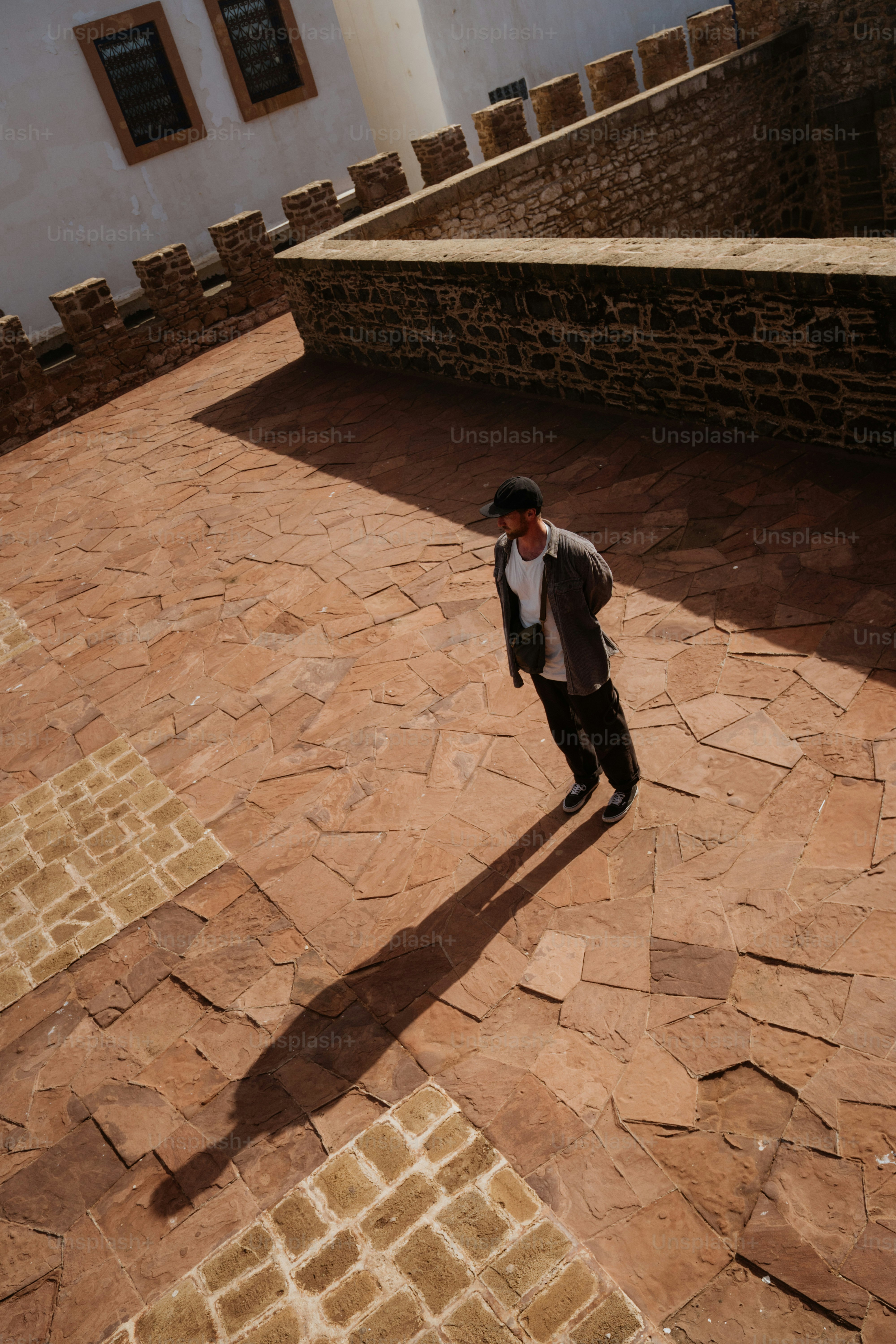 Man standing in a courtyard with long shadow