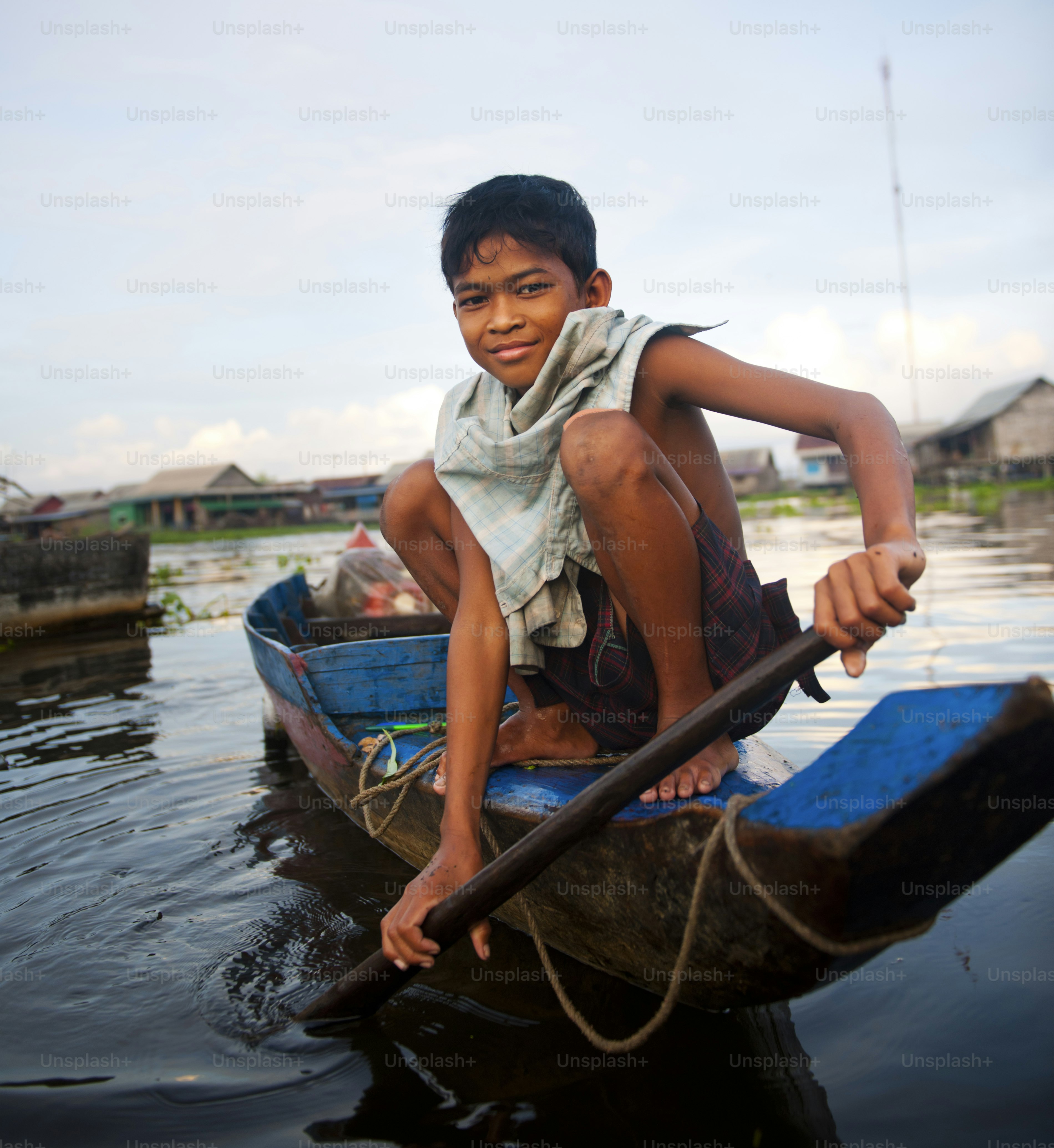 Cambodian boy travelling by boat in his floating village, Kampong Kleang, Cambodia.
