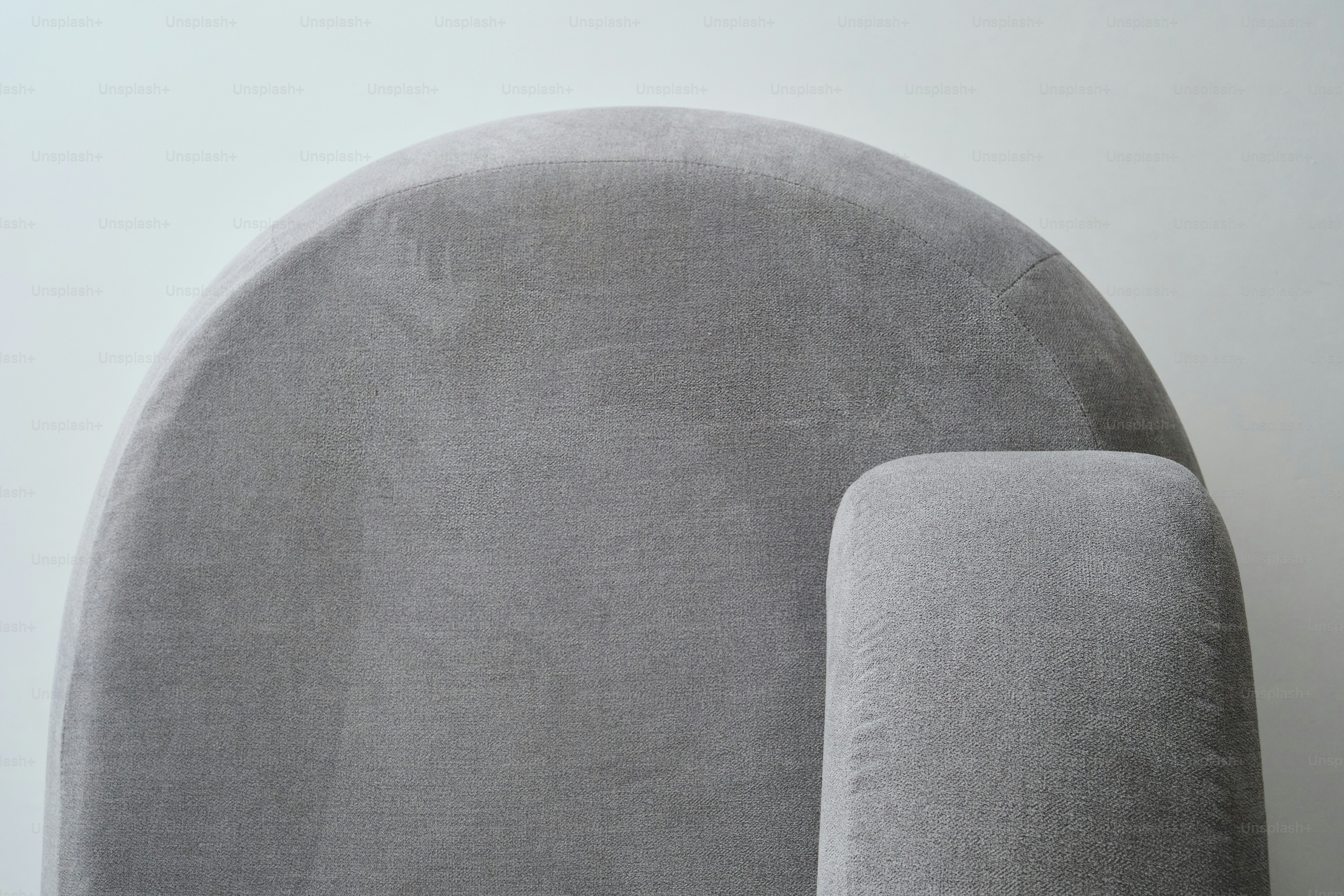 Primer plano de un sillón tapizado gris contra una pared blanca