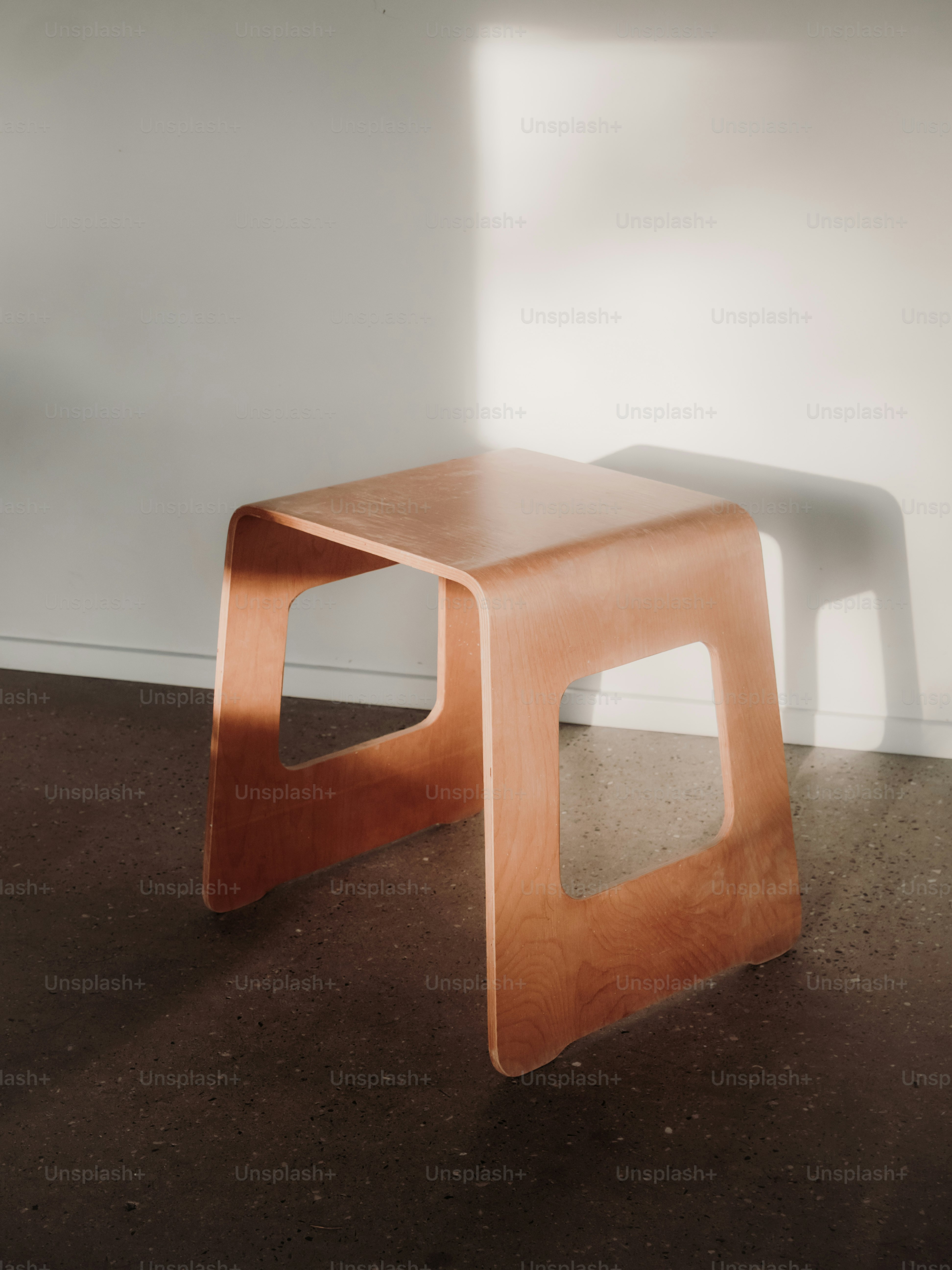 A modern wooden stool casts a shadow on the wall. photo – Interior ...