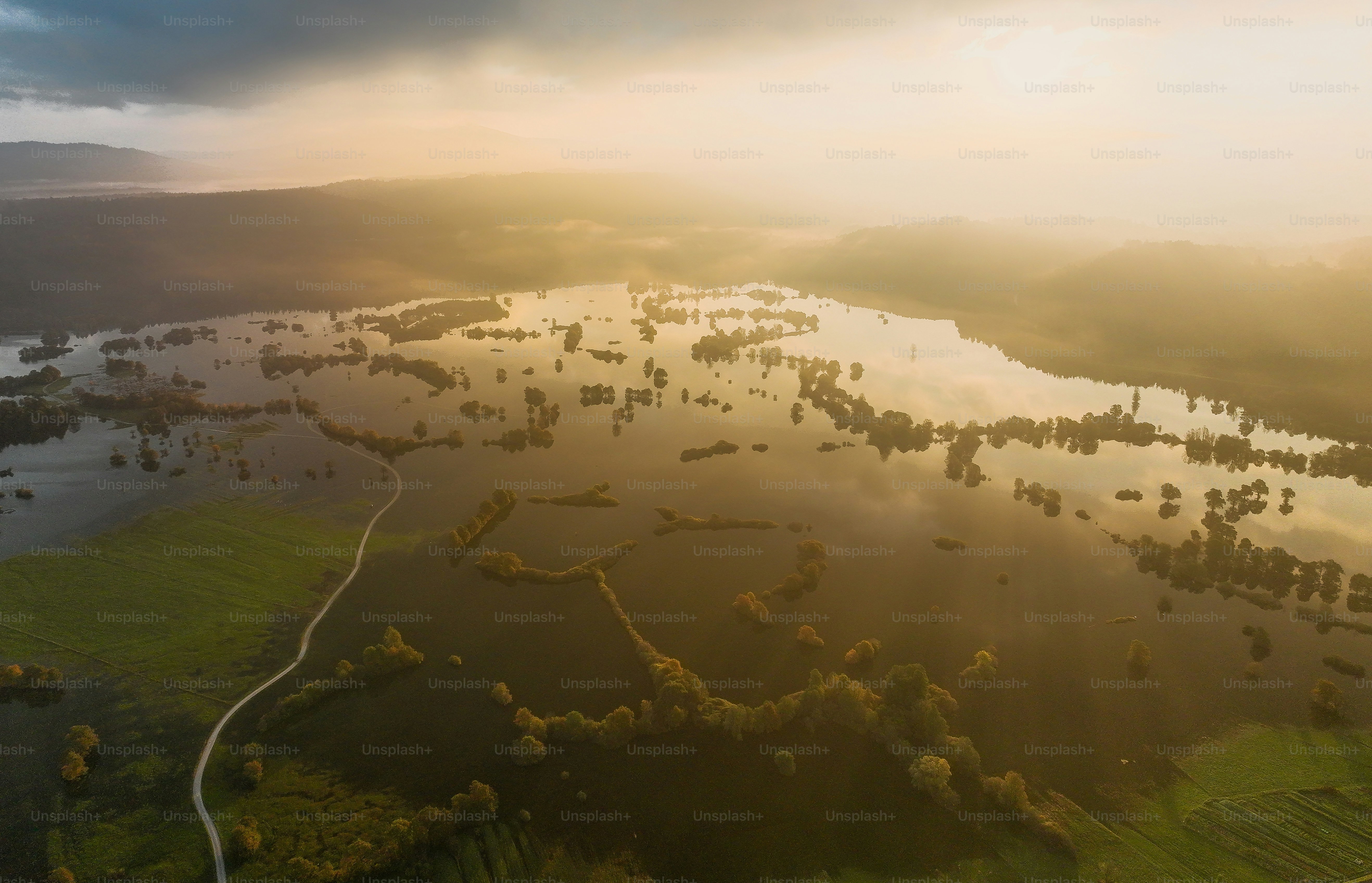 Überflutete Felder und Bäume unter einem nebligen Himmel