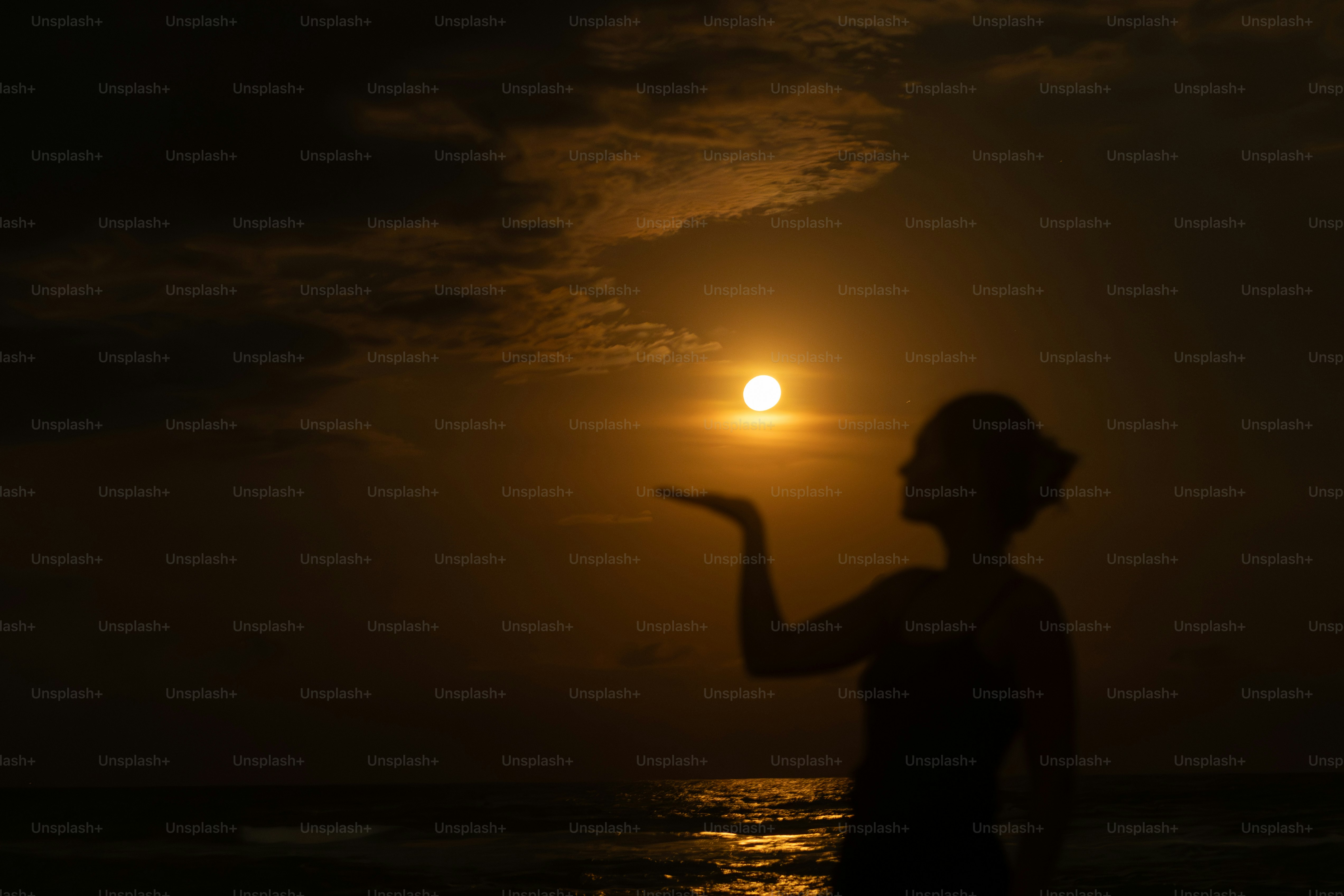 Woman holding the sun at sunset over the ocean photo – Beach Image on ...