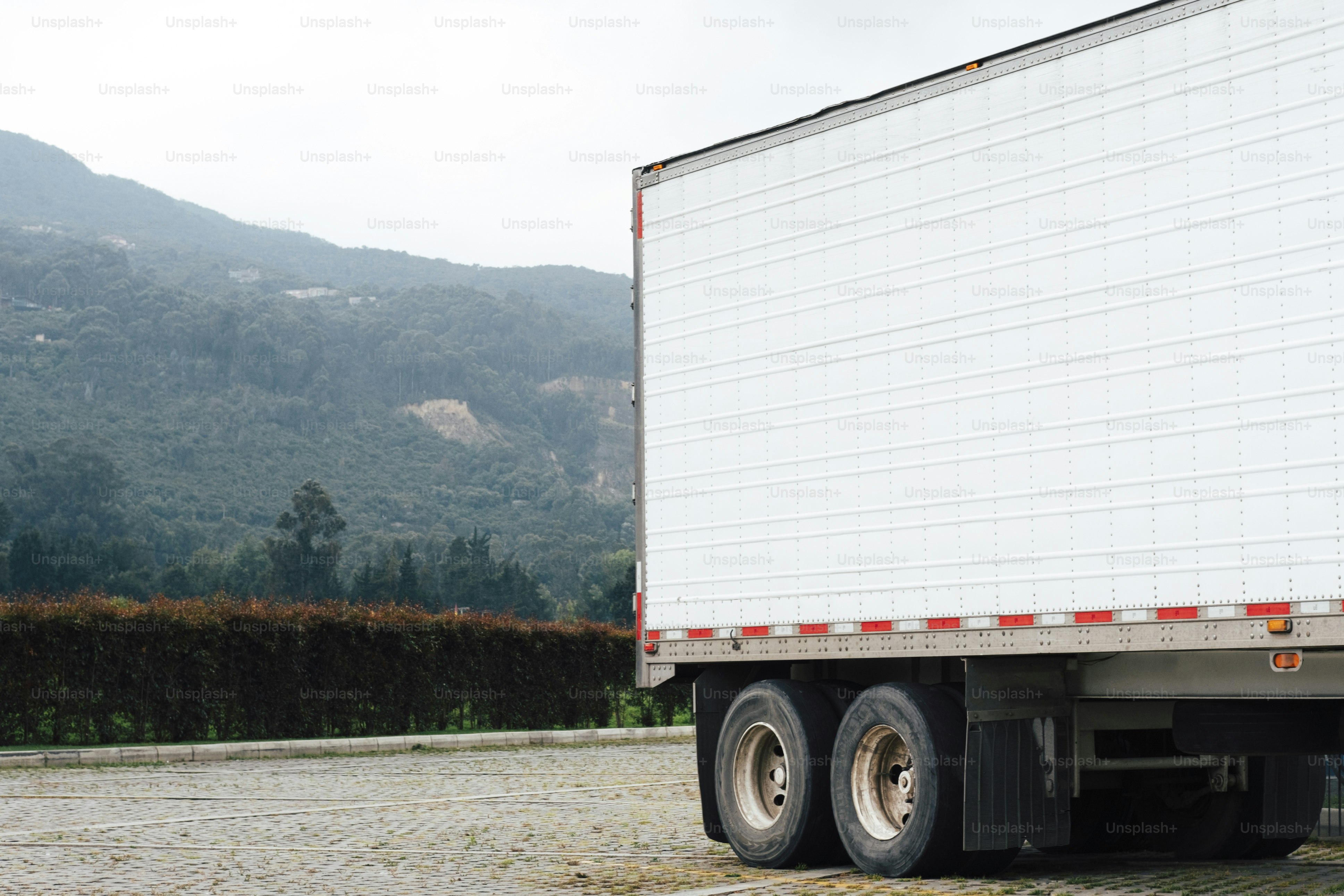 배경에 산이 보이는 흰색 세미 트레일러 트럭이 주차되어 있습니다