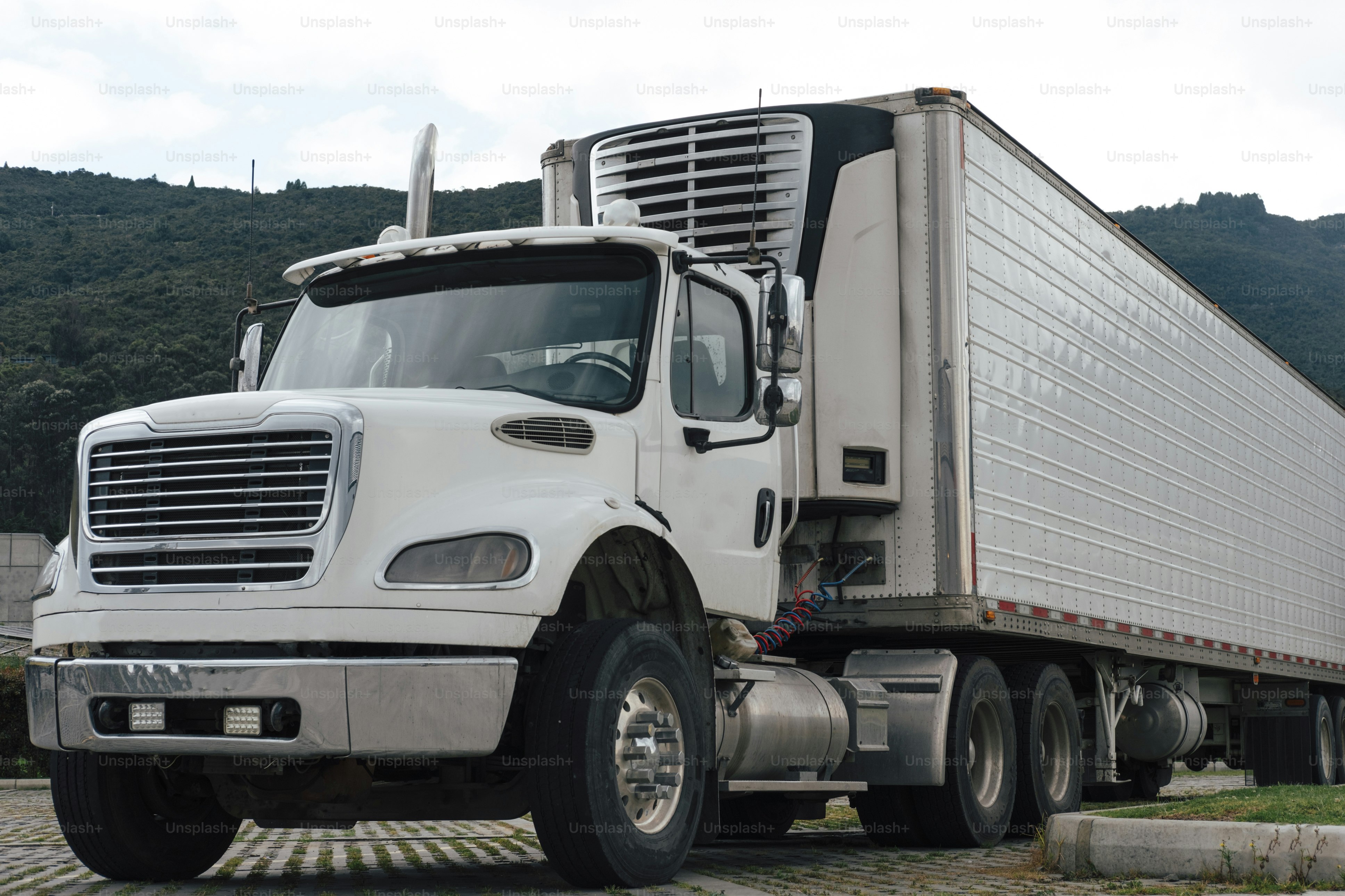 긴 트레일러가 주차된 흰색 세미트럭.