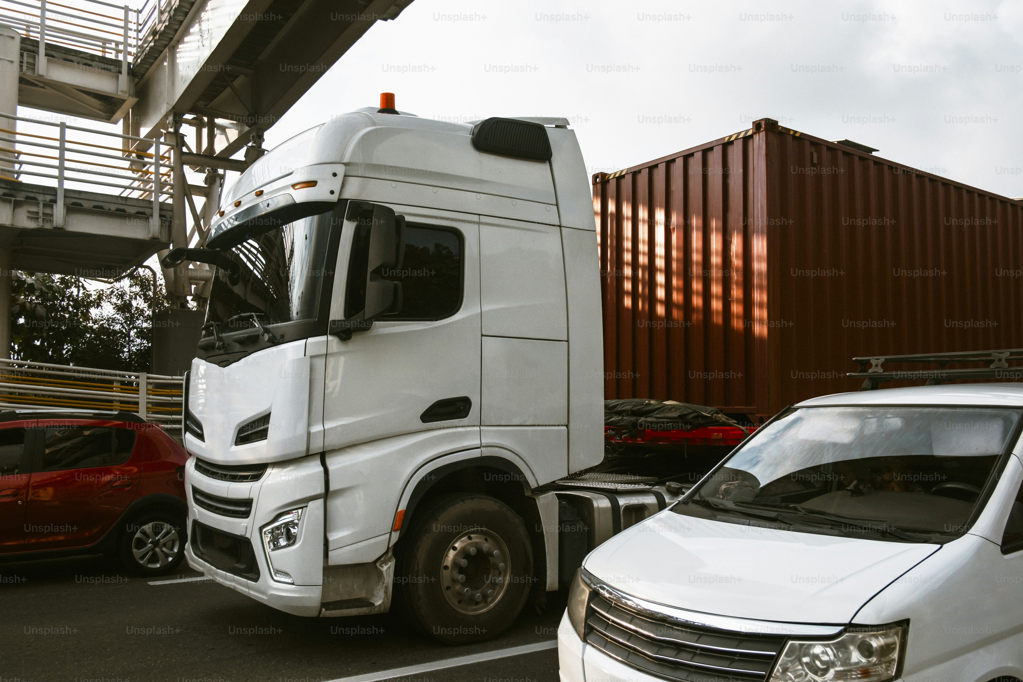 빨간색 컨테이너 옆에 흰색 세미 트럭이 주차되어 있었다.