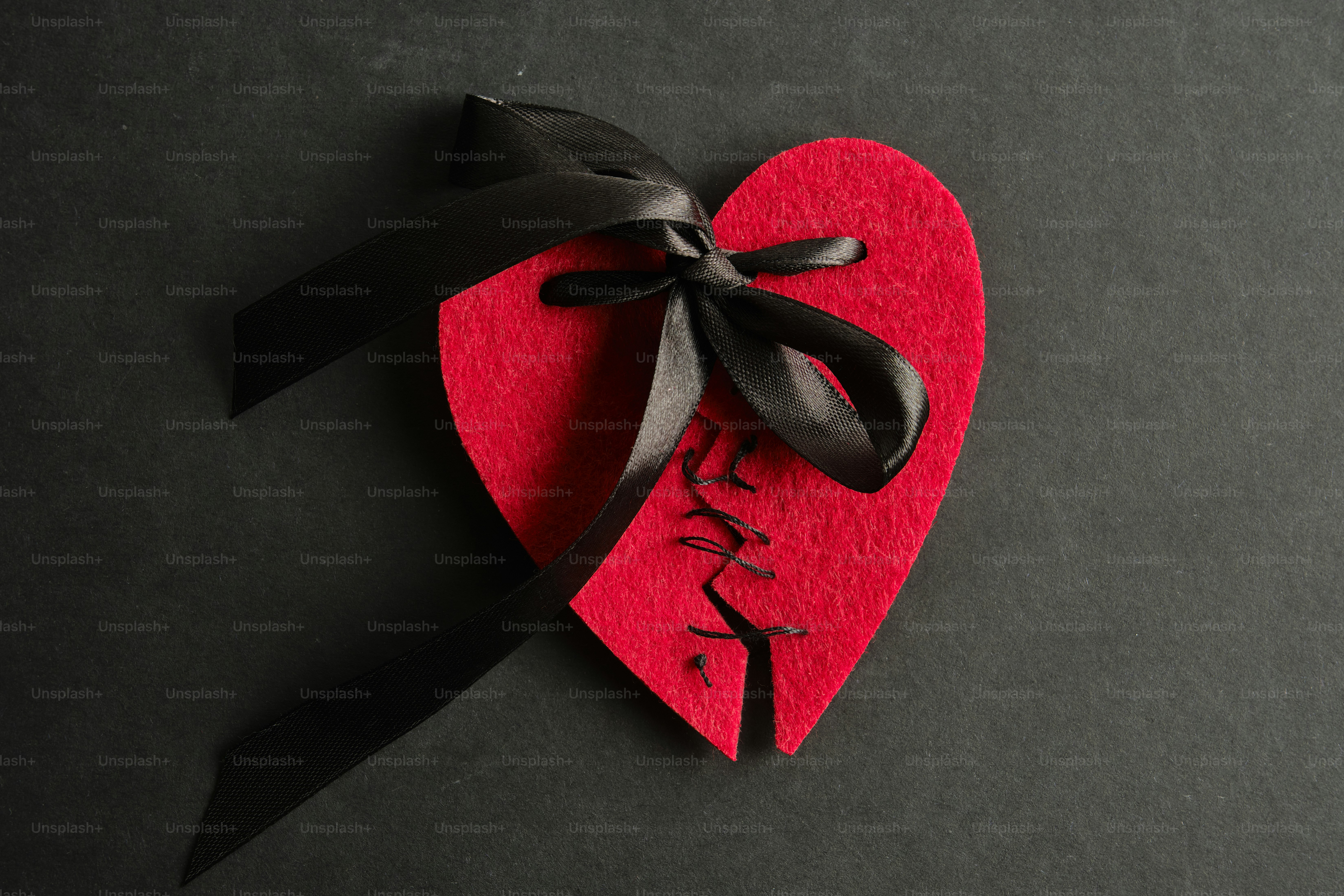 A broken red heart with a black ribbon