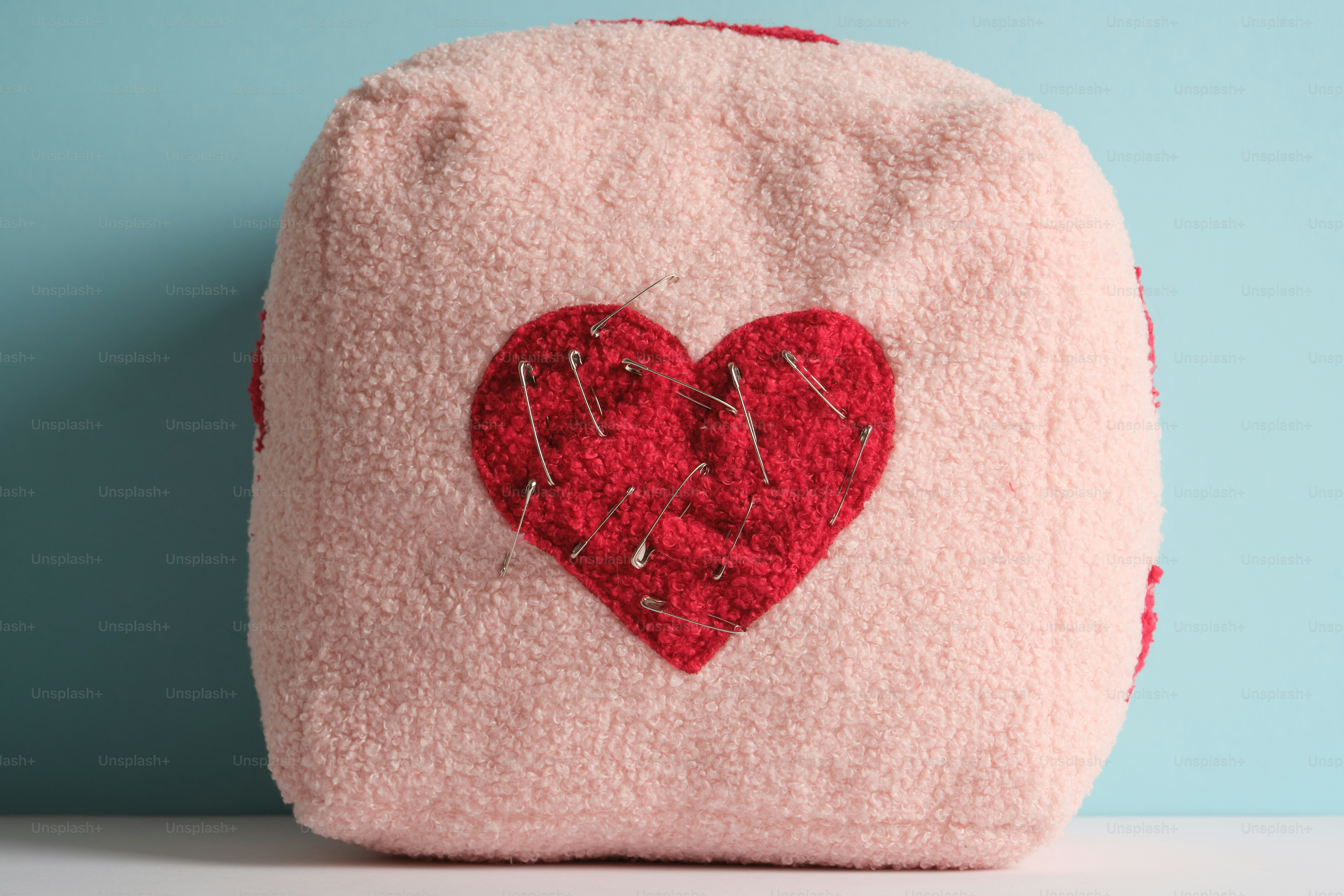 Un cuore di peluche rosa con un cucito rosso