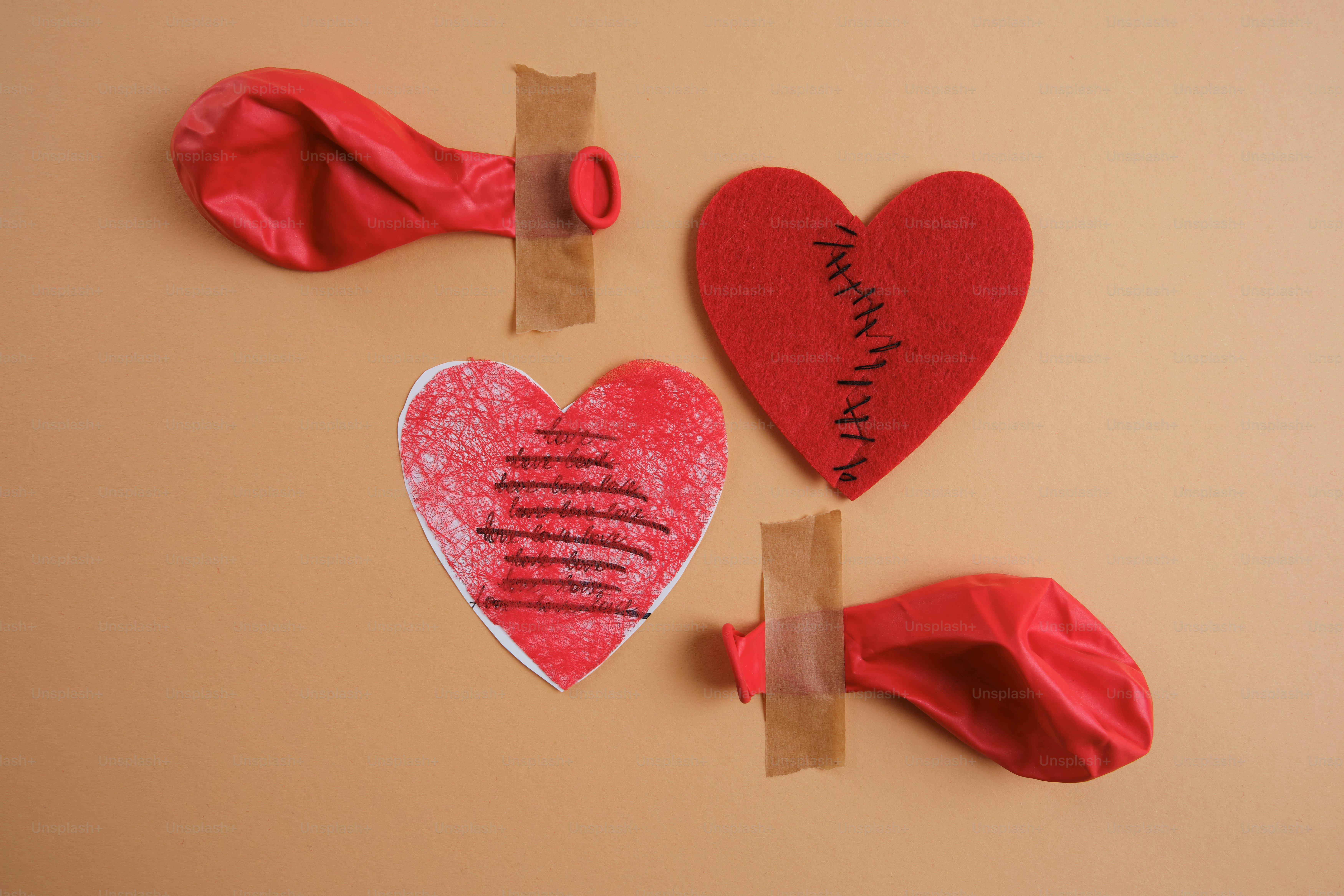 Due cuori rossi e palloncini sgonfiati su sfondo color beige