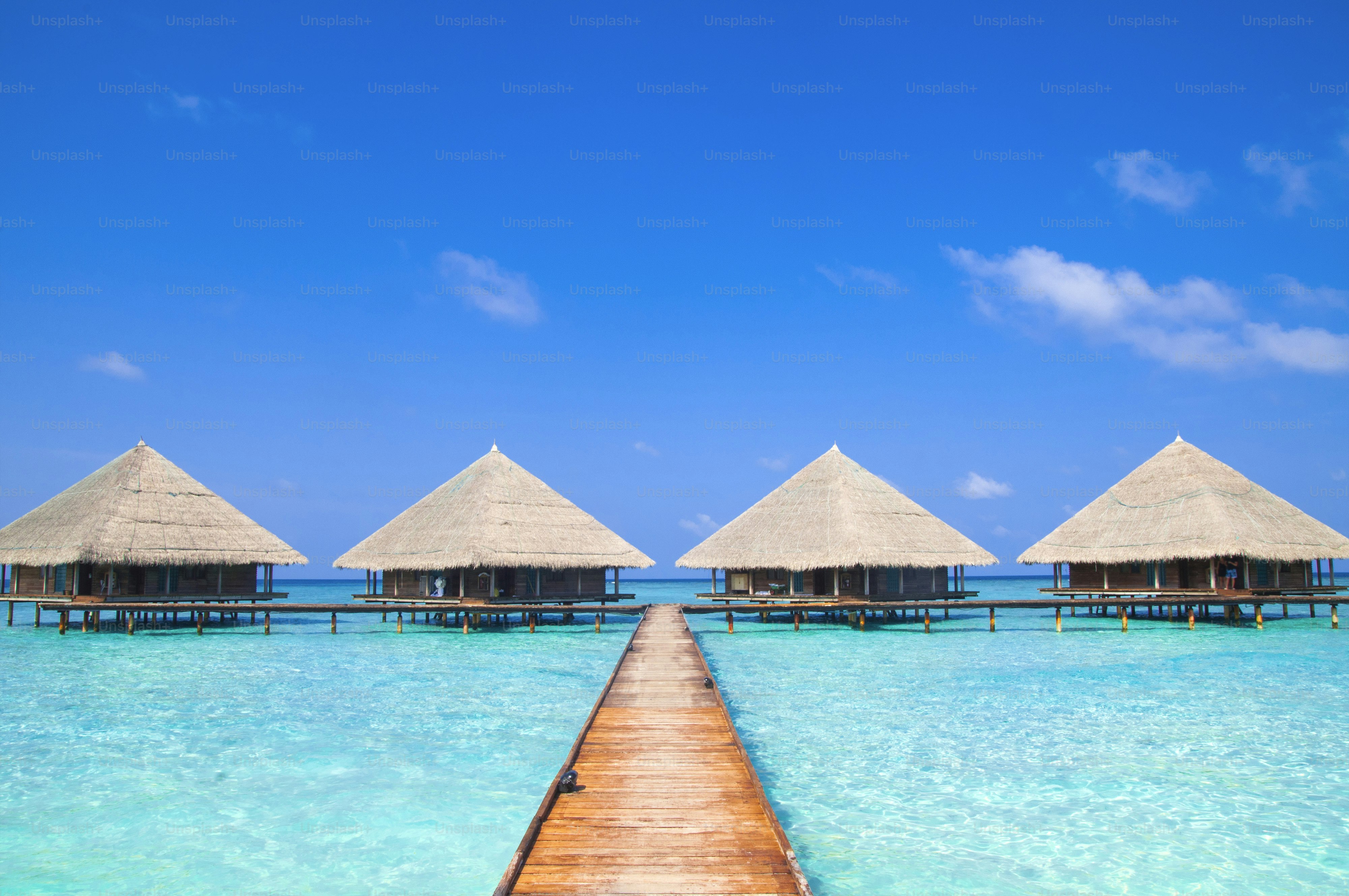Four overwater bungalows connected by a wooden walkway