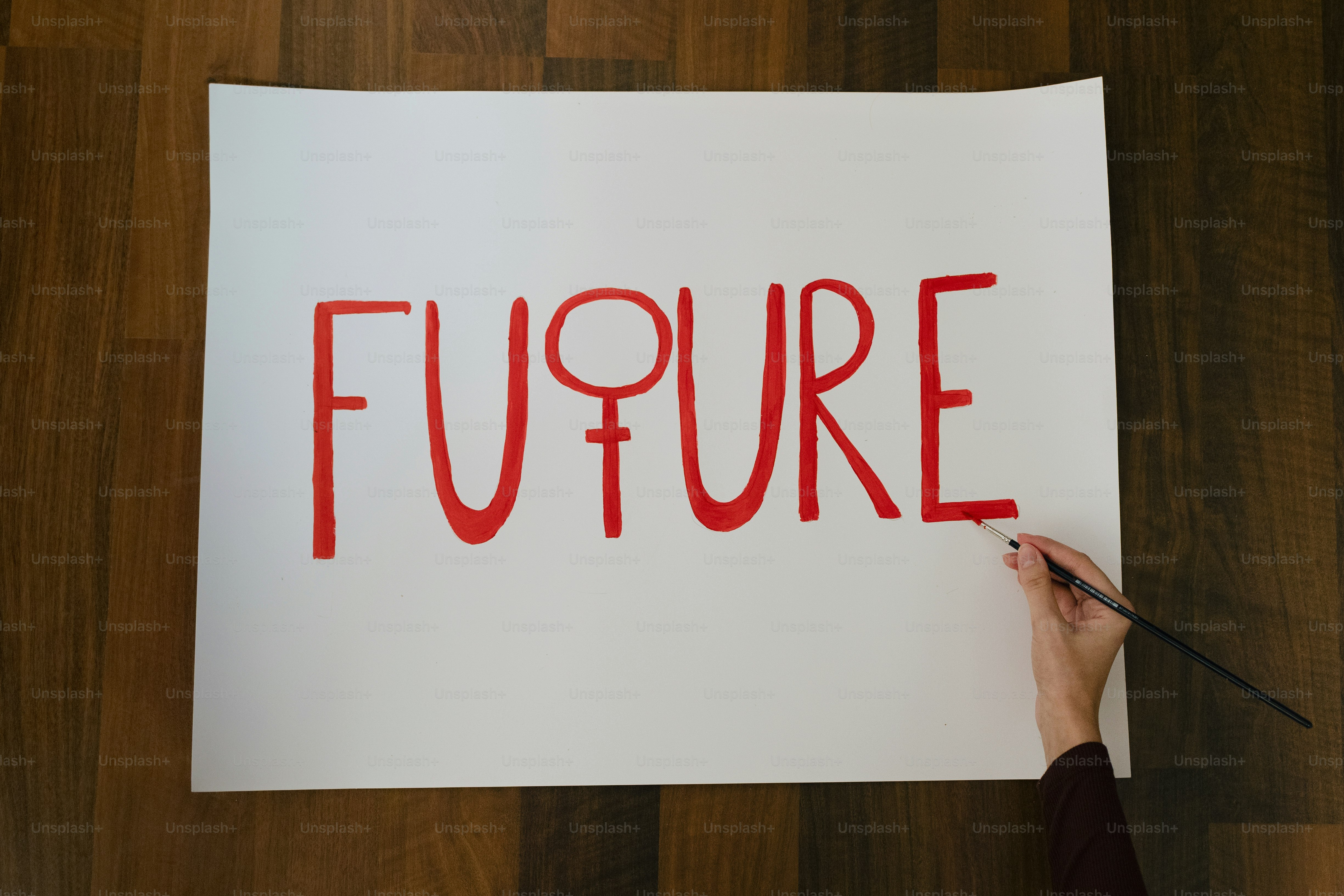 Hand paints the word future with female symbol.
