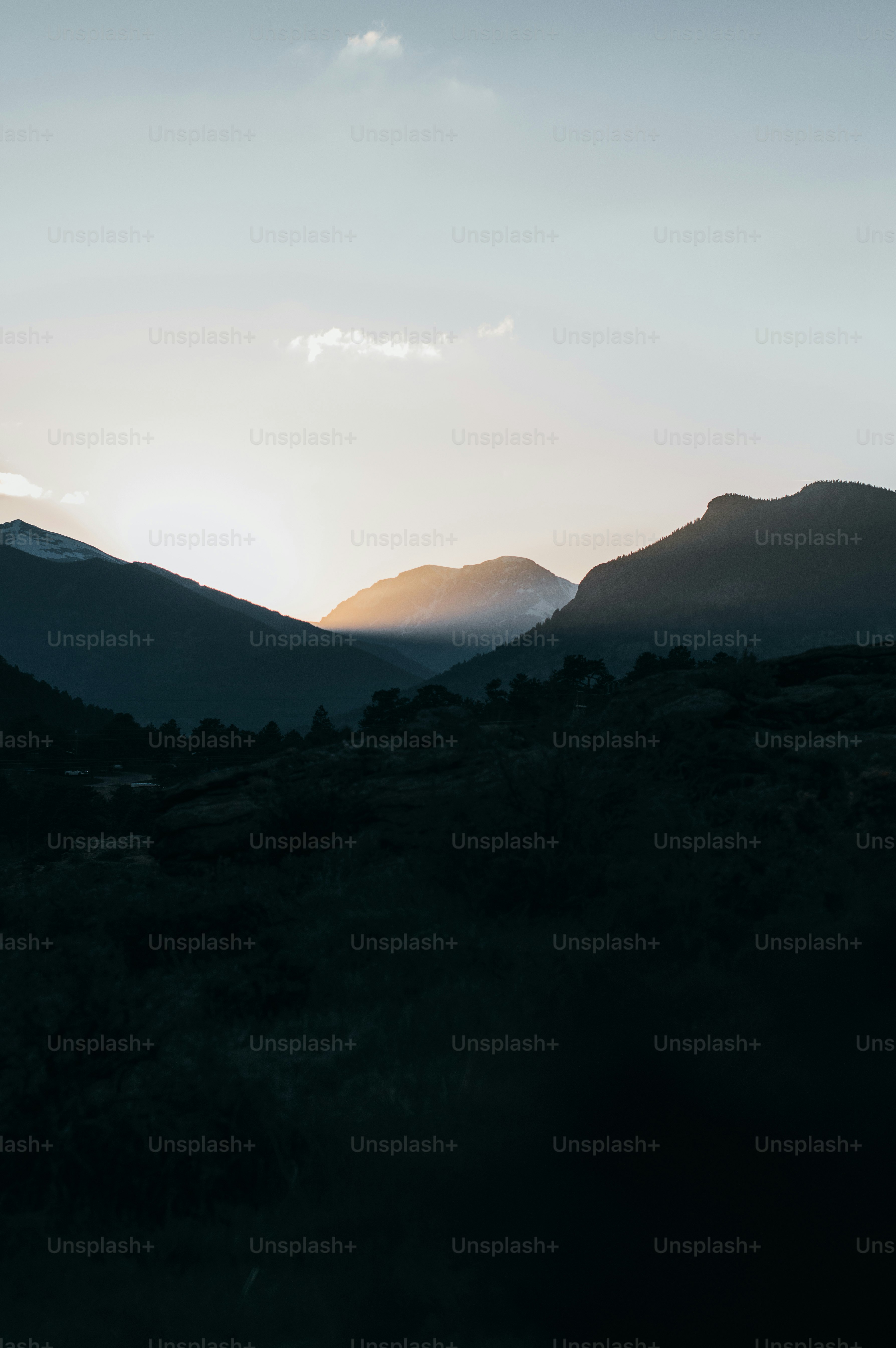 Silhouettes of mountains against a bright sky at dusk