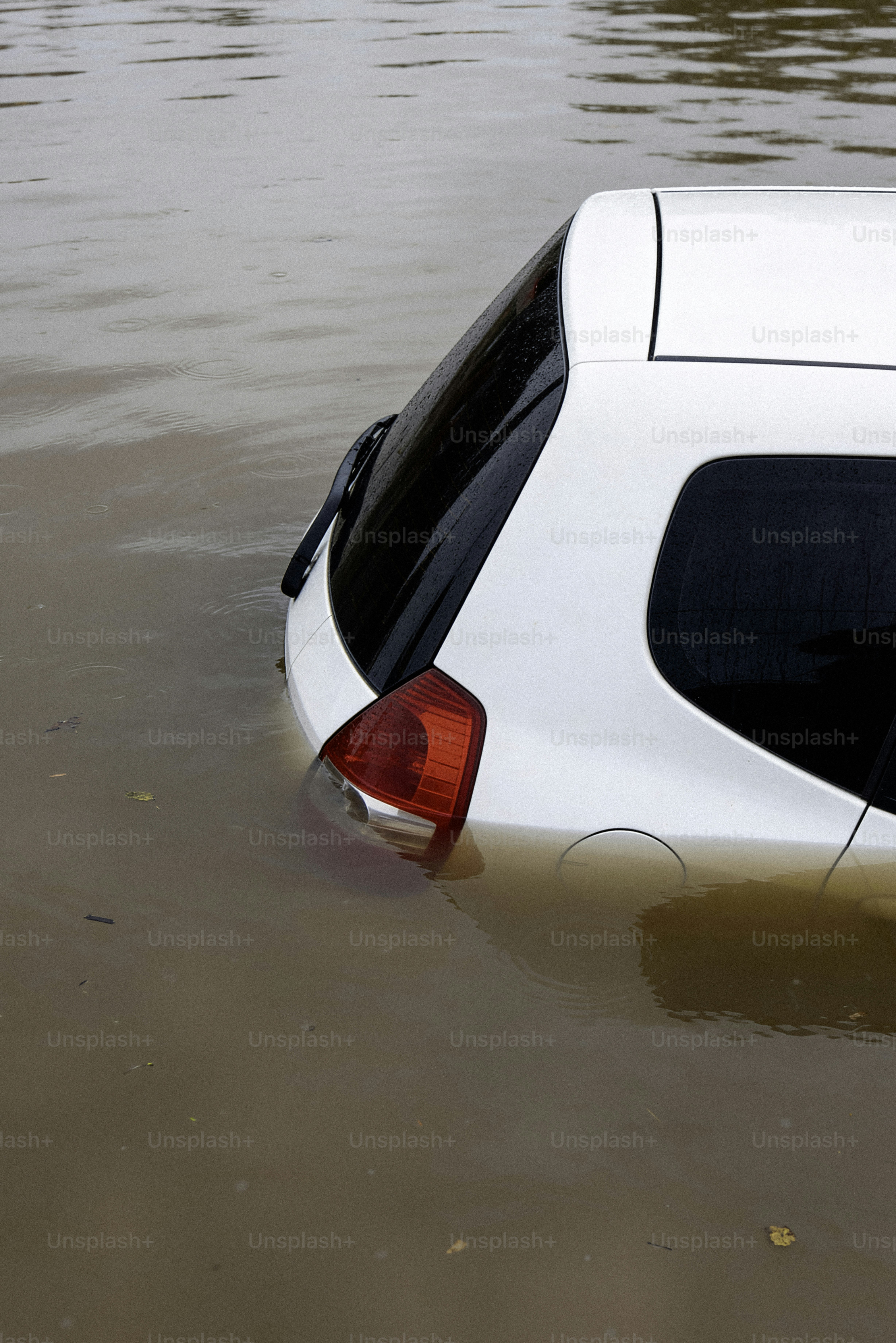 Un'auto bianca sommersa in acque torbide