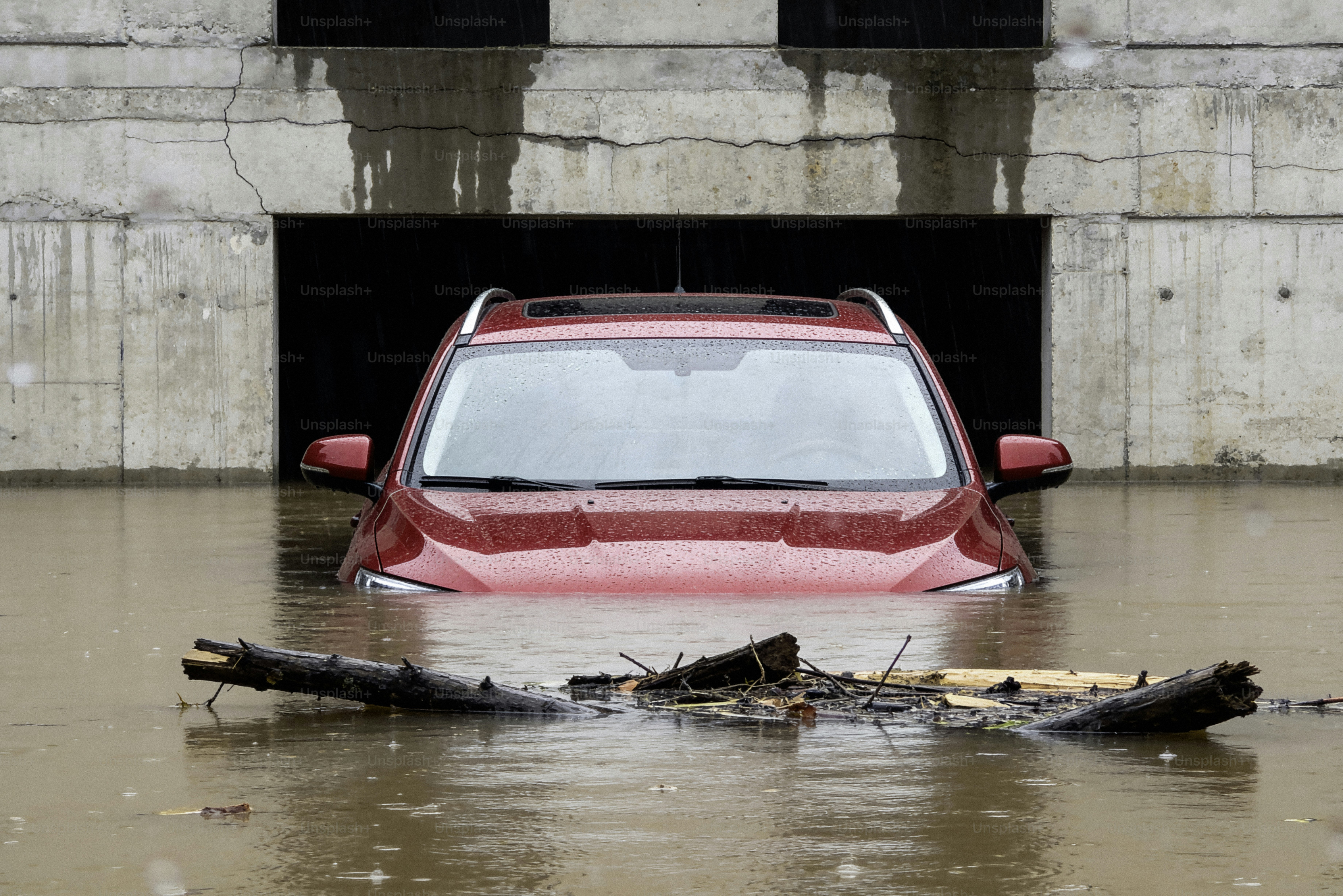 SUV rosso sommerso nelle acque piene di detriti.