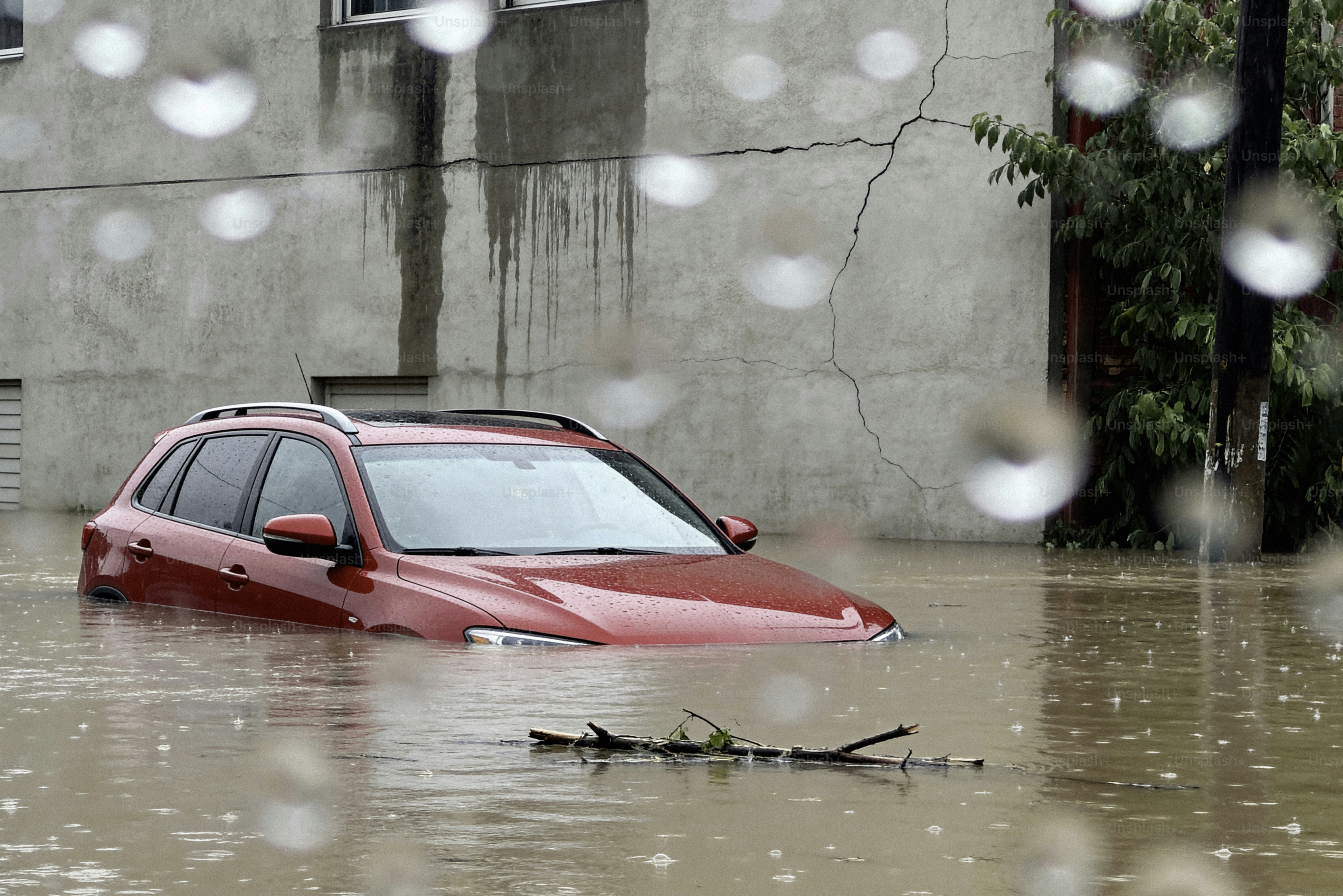 Auto rossa sommersa nelle acque vicino a un edificio.