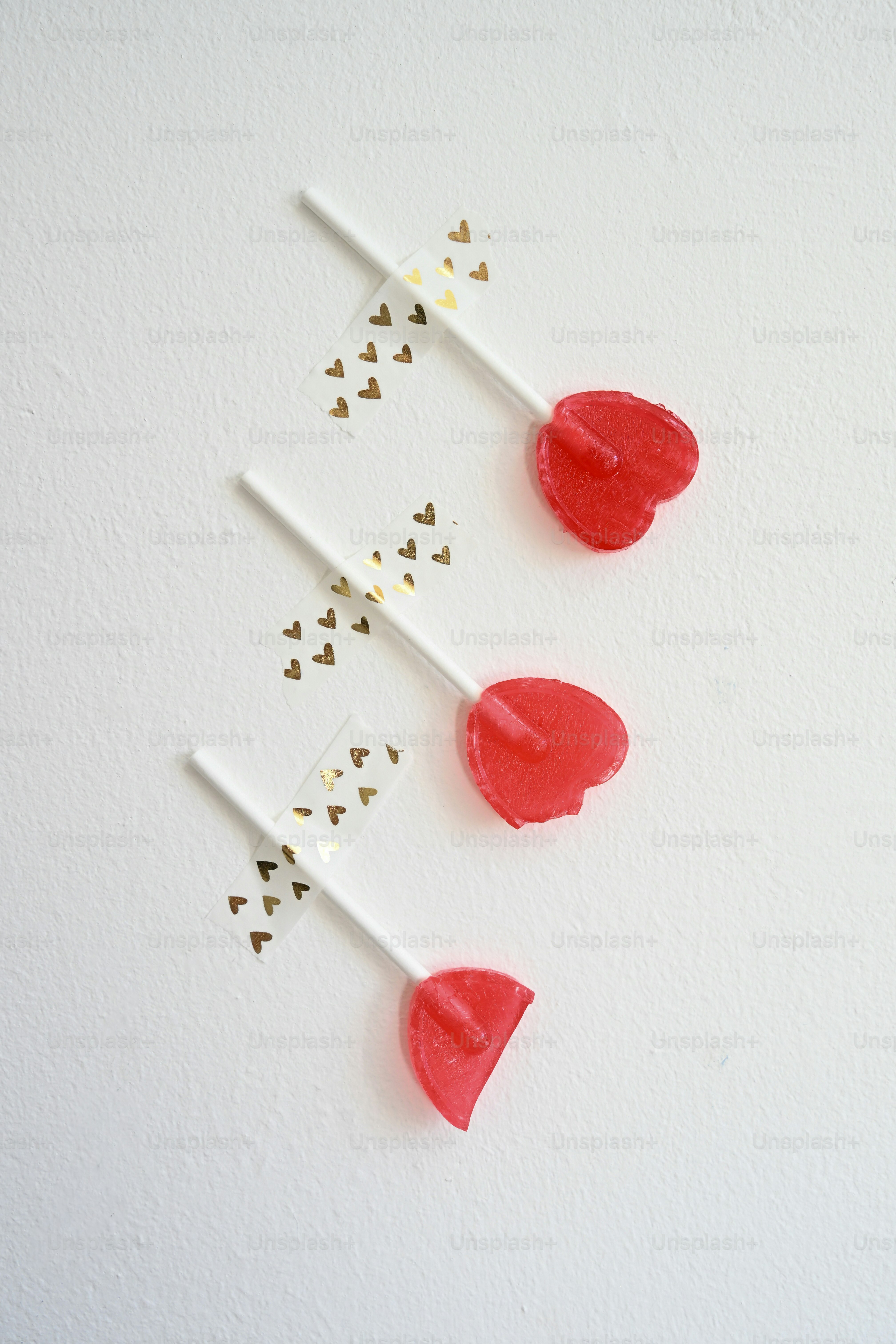 Three heart-shaped lollipops with gold heart tape