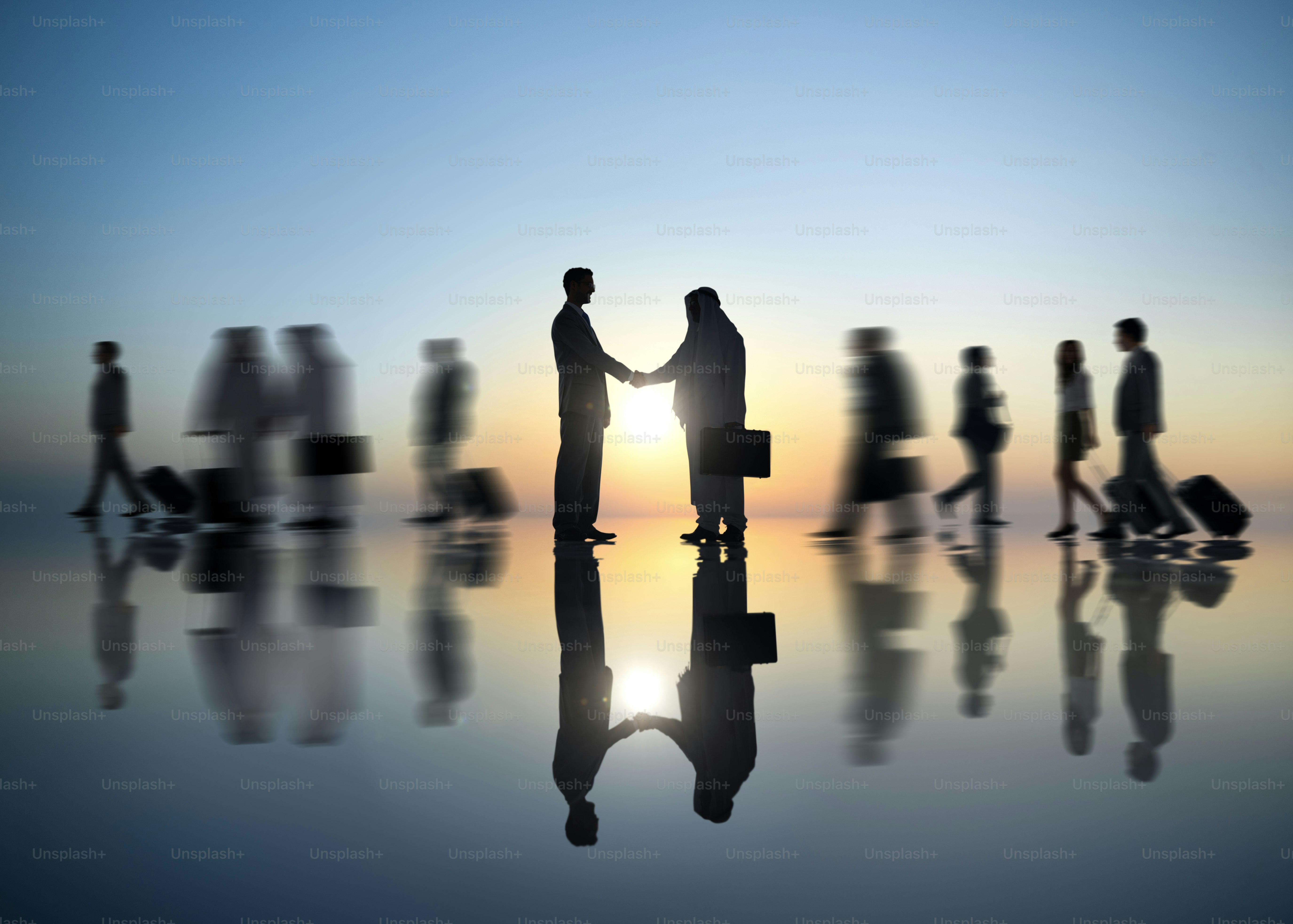 Business people shaking hands at sunset with reflections