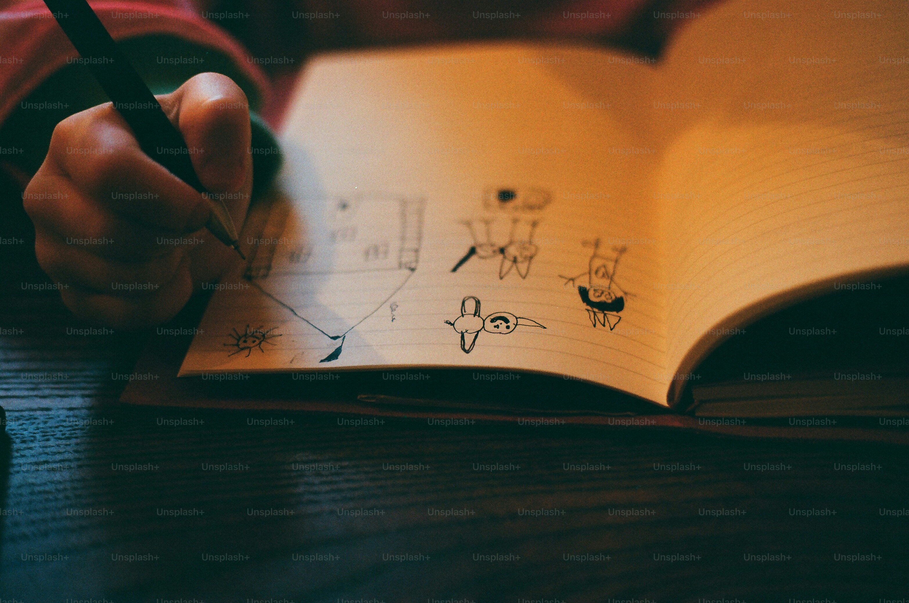 A person drawing small figures in a notebook