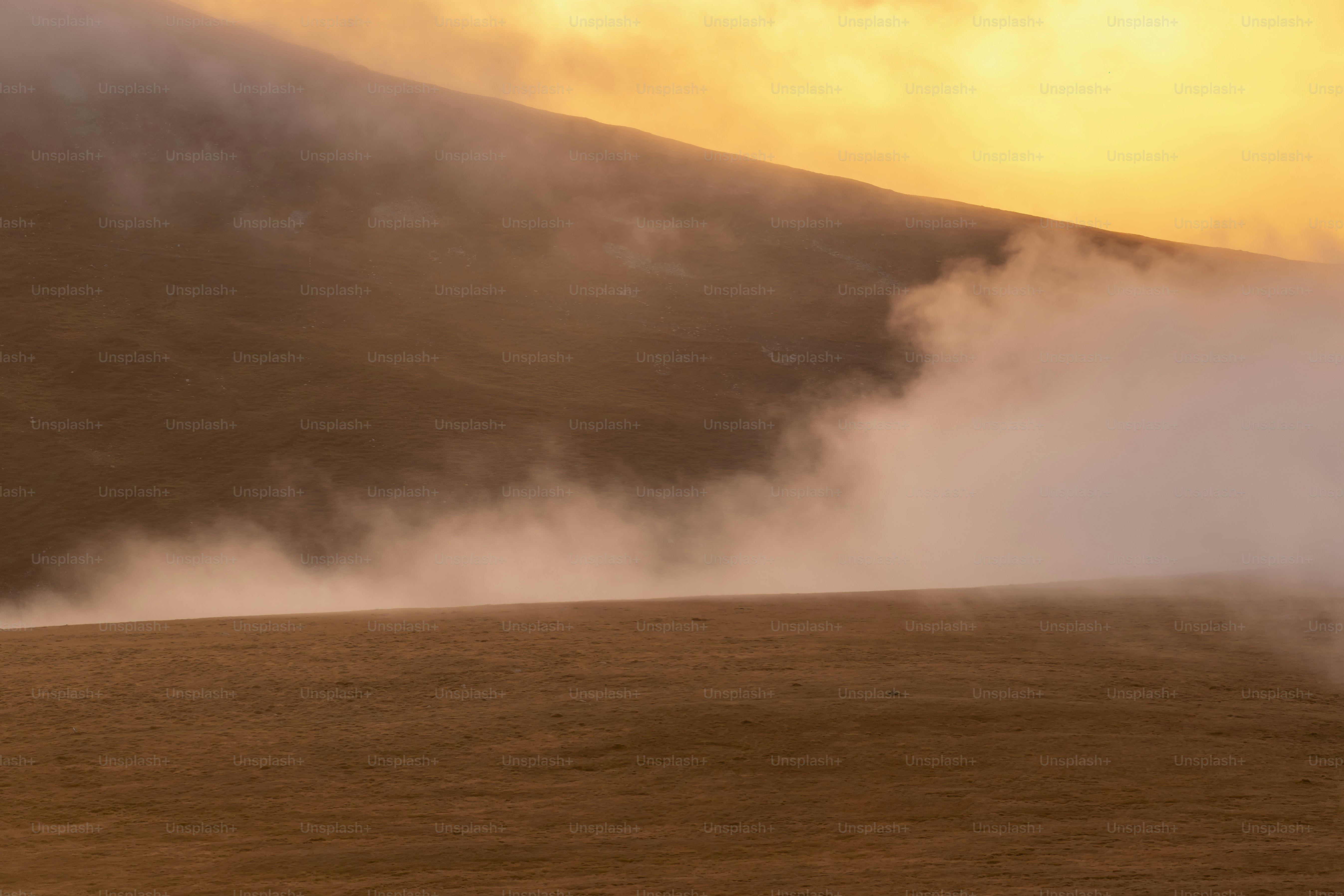 Cielo dorato sopra pendii nebbiosi di montagna all'alba