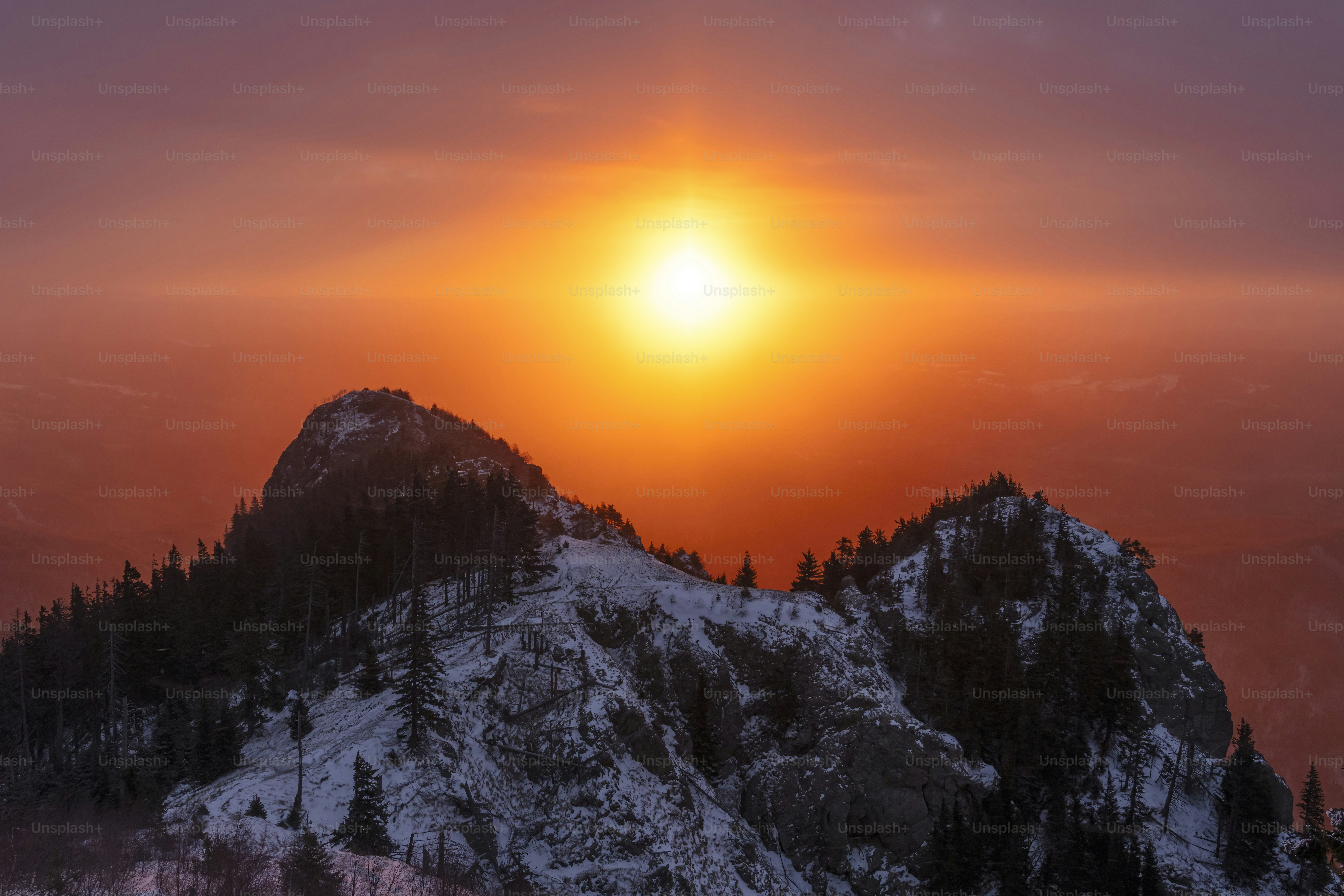 Il sole tramontava su una cima montuosa coperta di neve.