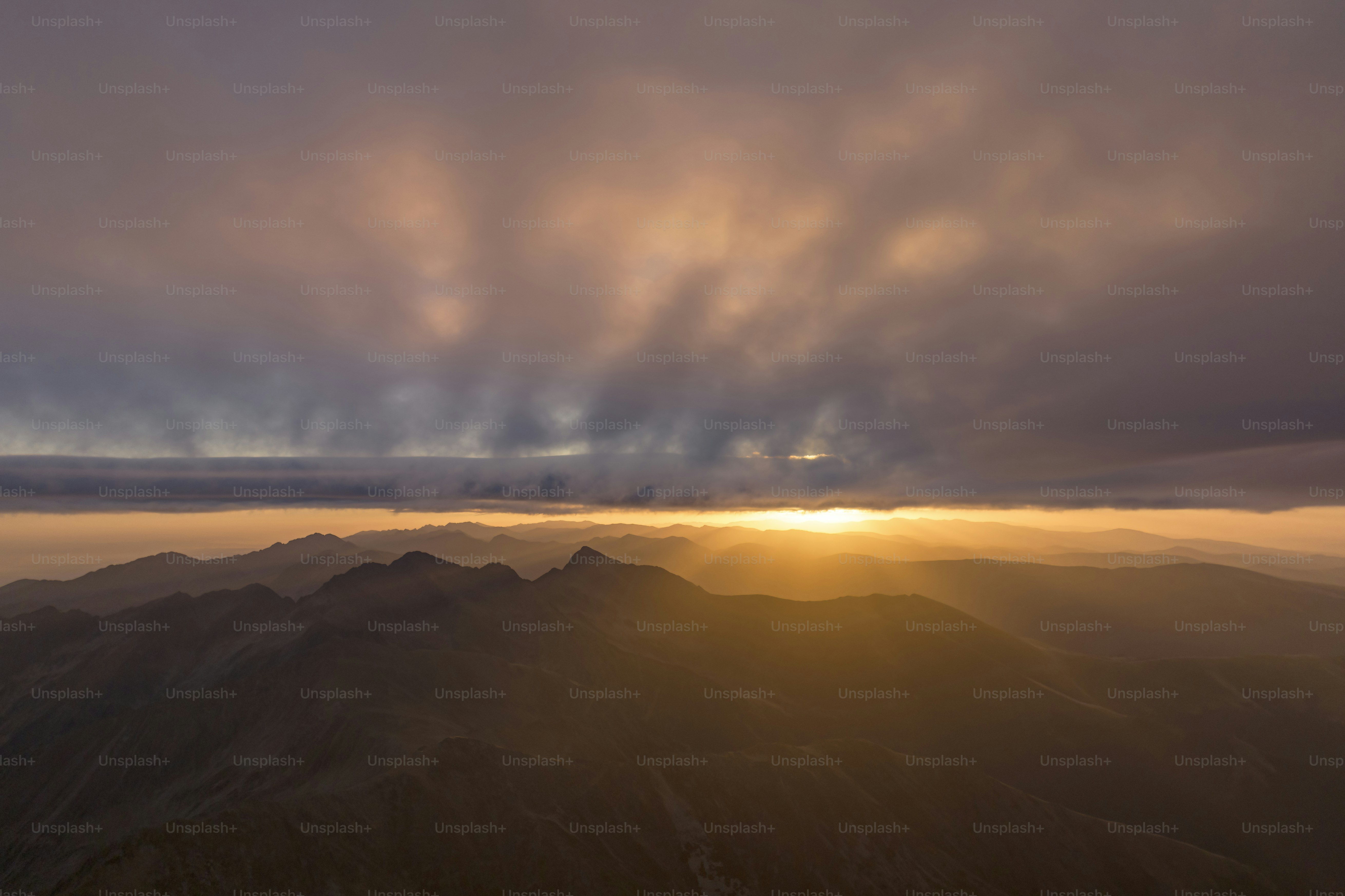 Alba su una catena montuosa nebbiosa con nuvole drammatiche