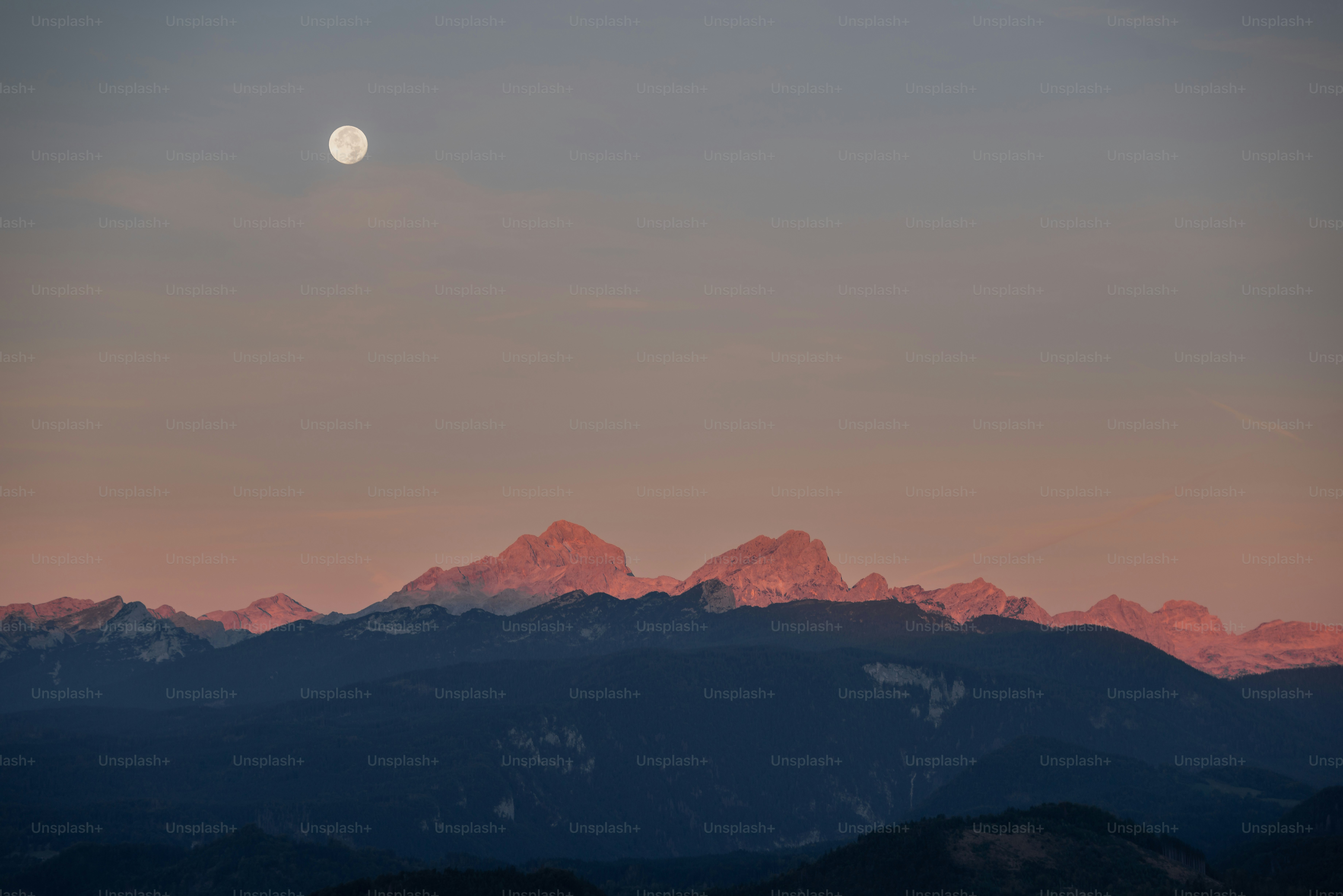 Pleine lune sur des montagnes en silhouette au crépuscule