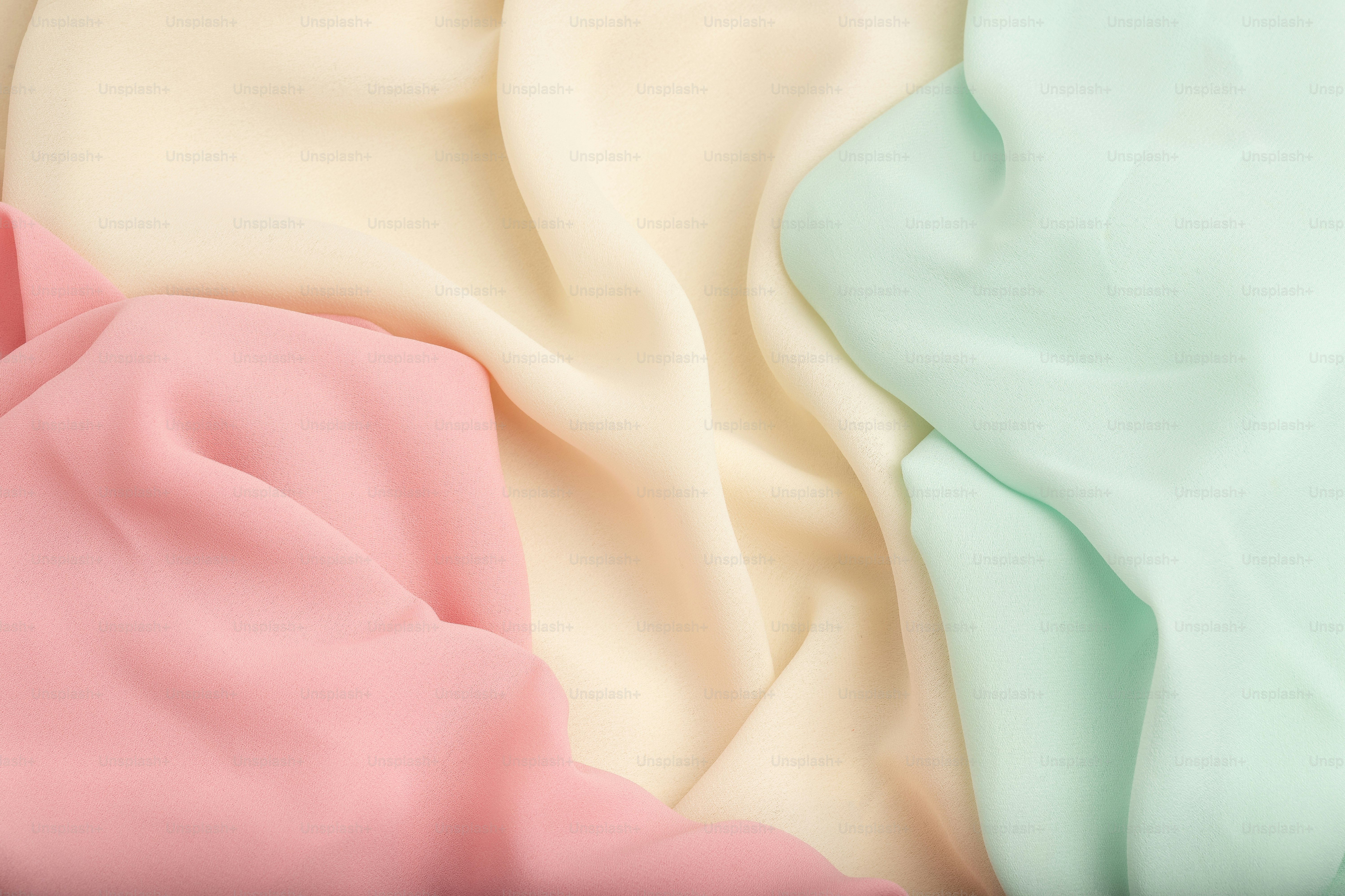 Three colors of draped fabric: pink, cream, and mint.