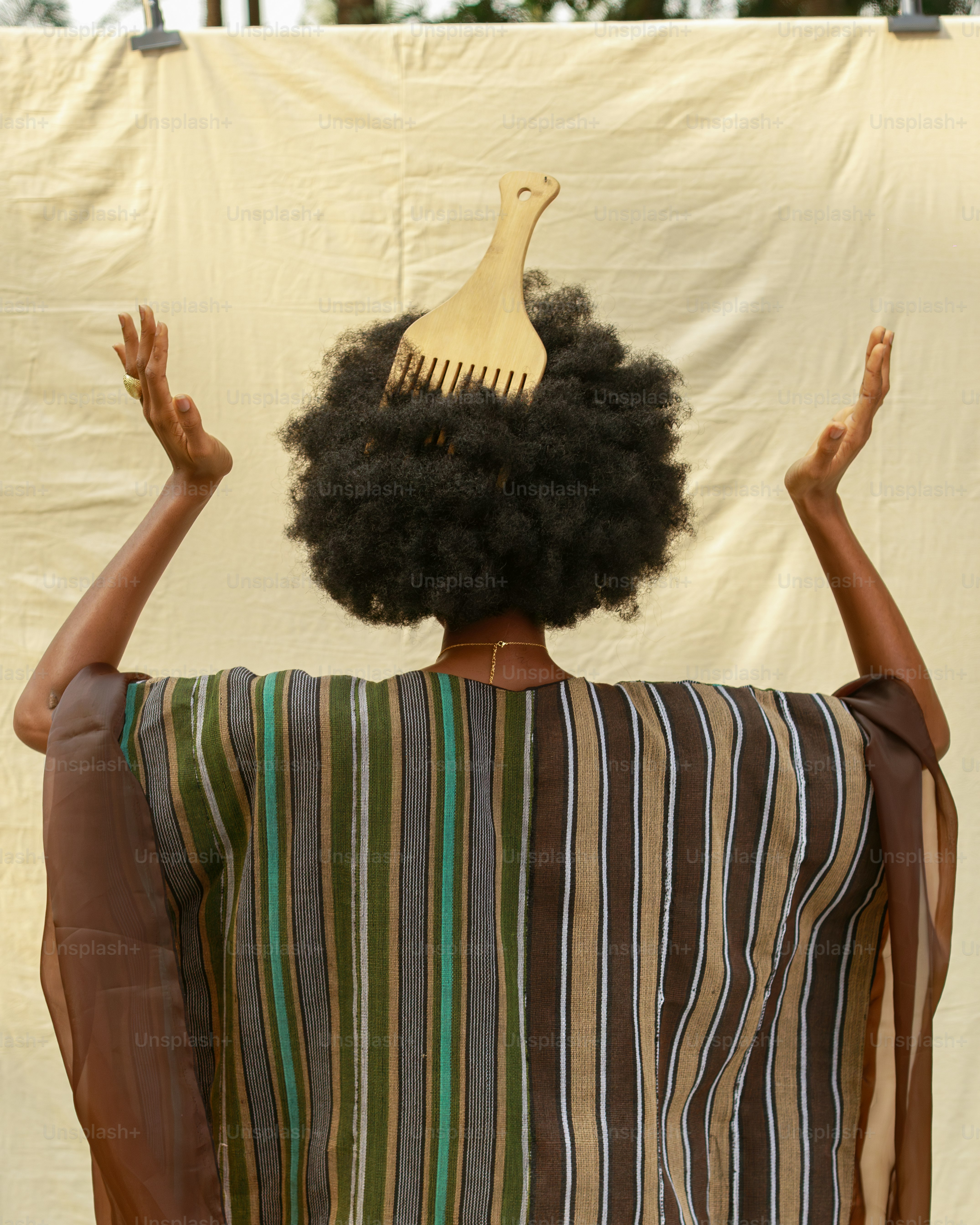 Woman with afro and wooden comb raises hands. photo – Fashion Image on ...