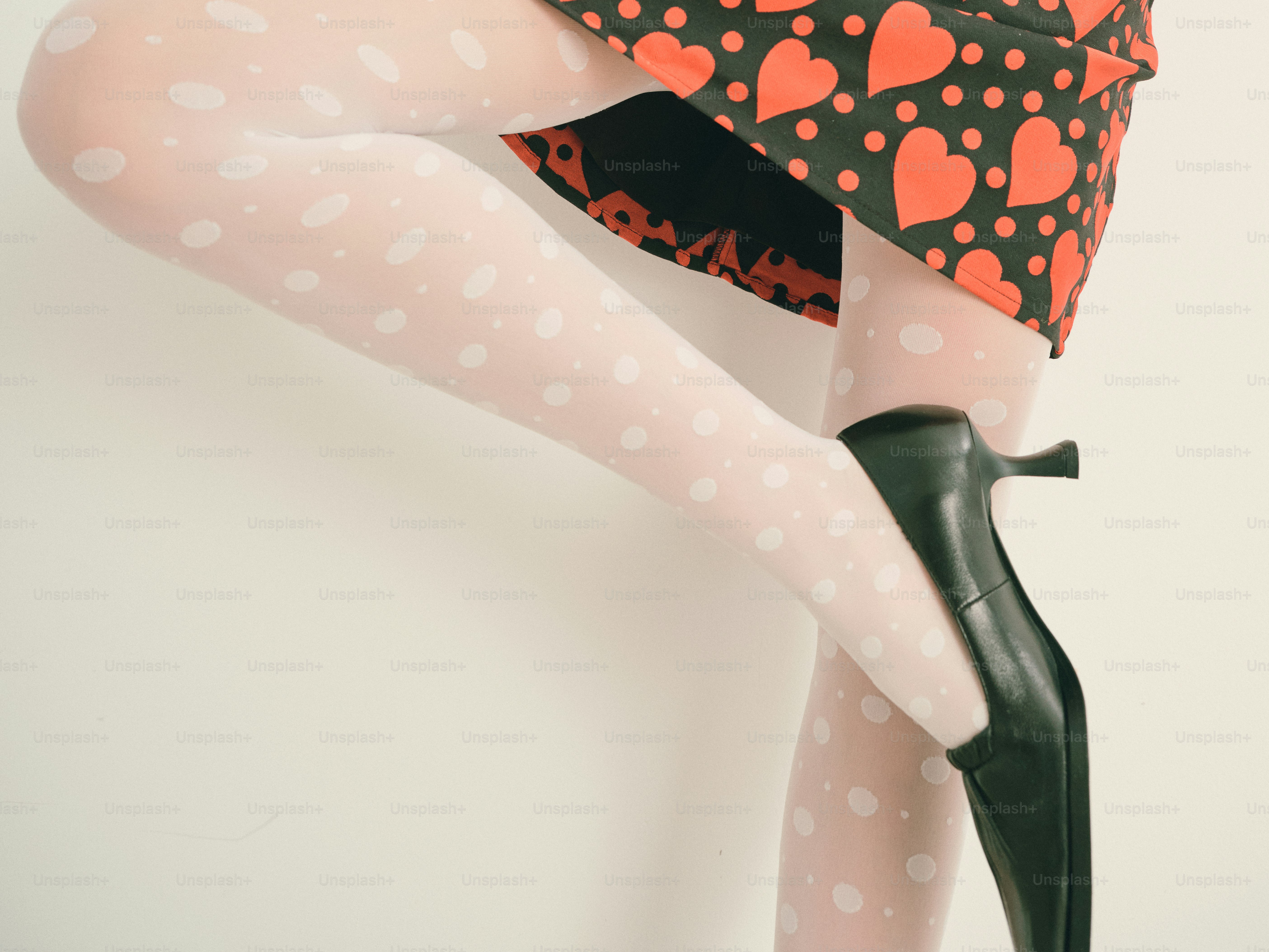 흰색 물방울 무늬 타이츠와 검은색 하이힐을 신은 여성의 다리.