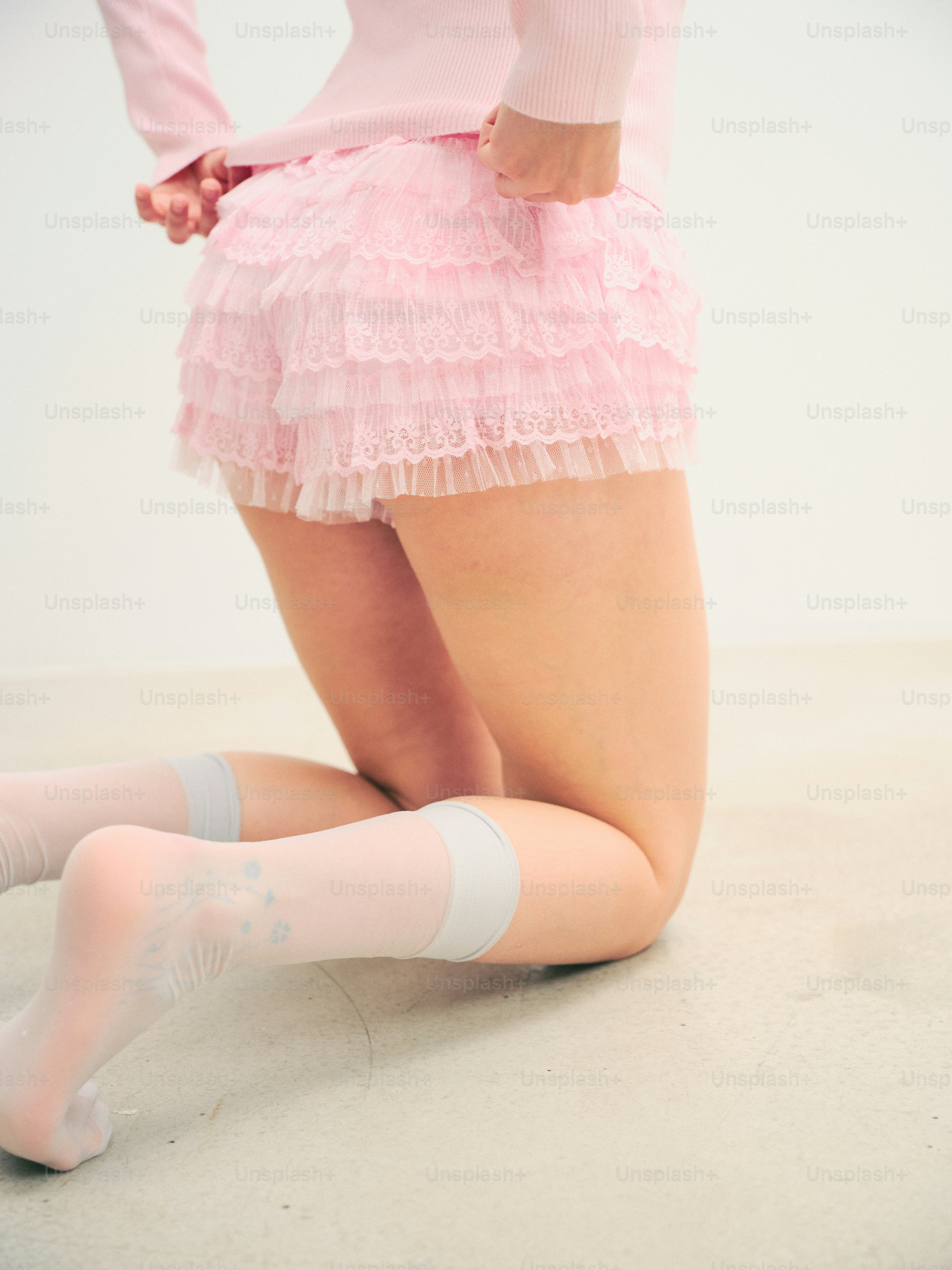 A person in pink ruffled shorts and thigh-high socks
