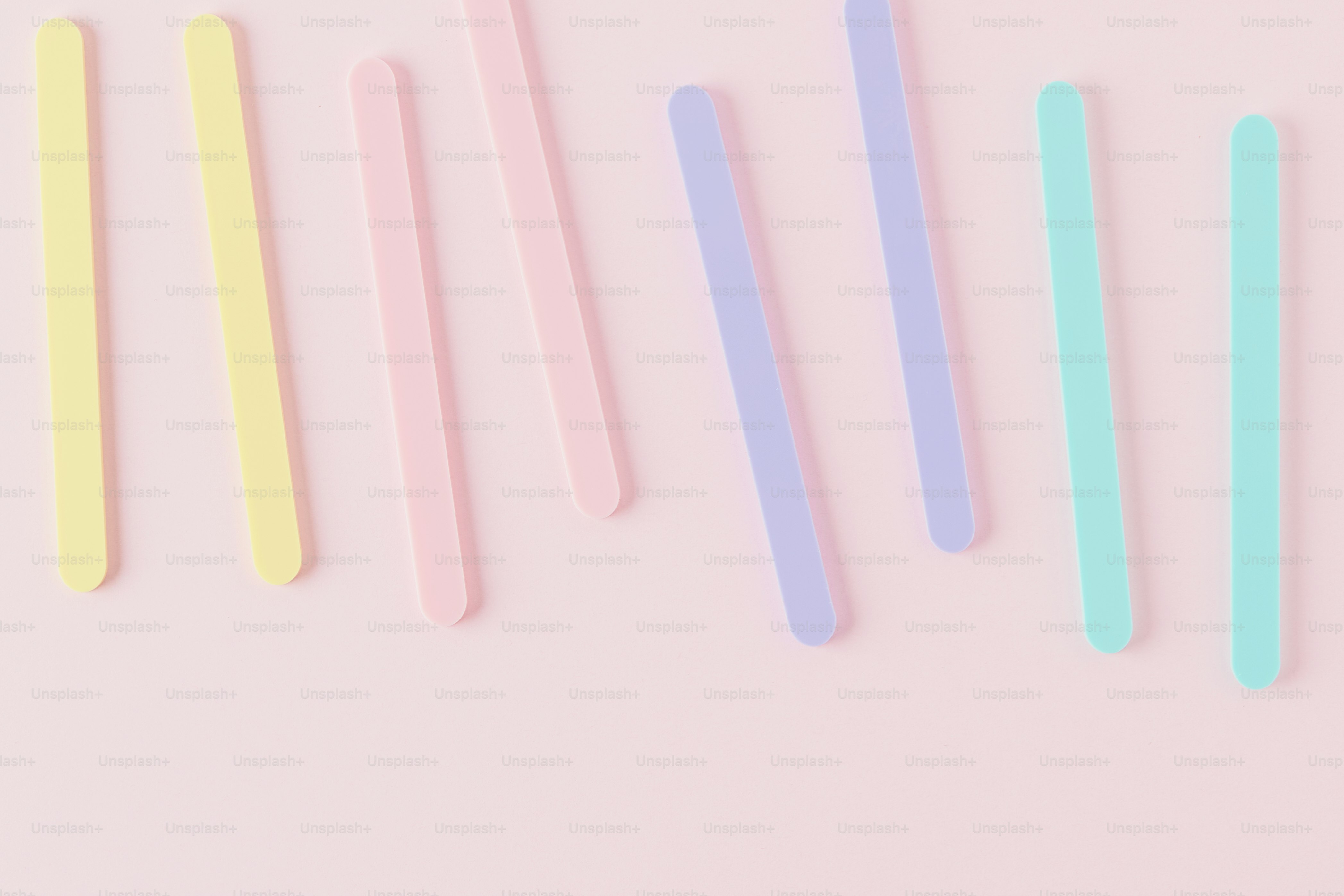 Pastel colored sticks scattered on a pink background photo – Background ...