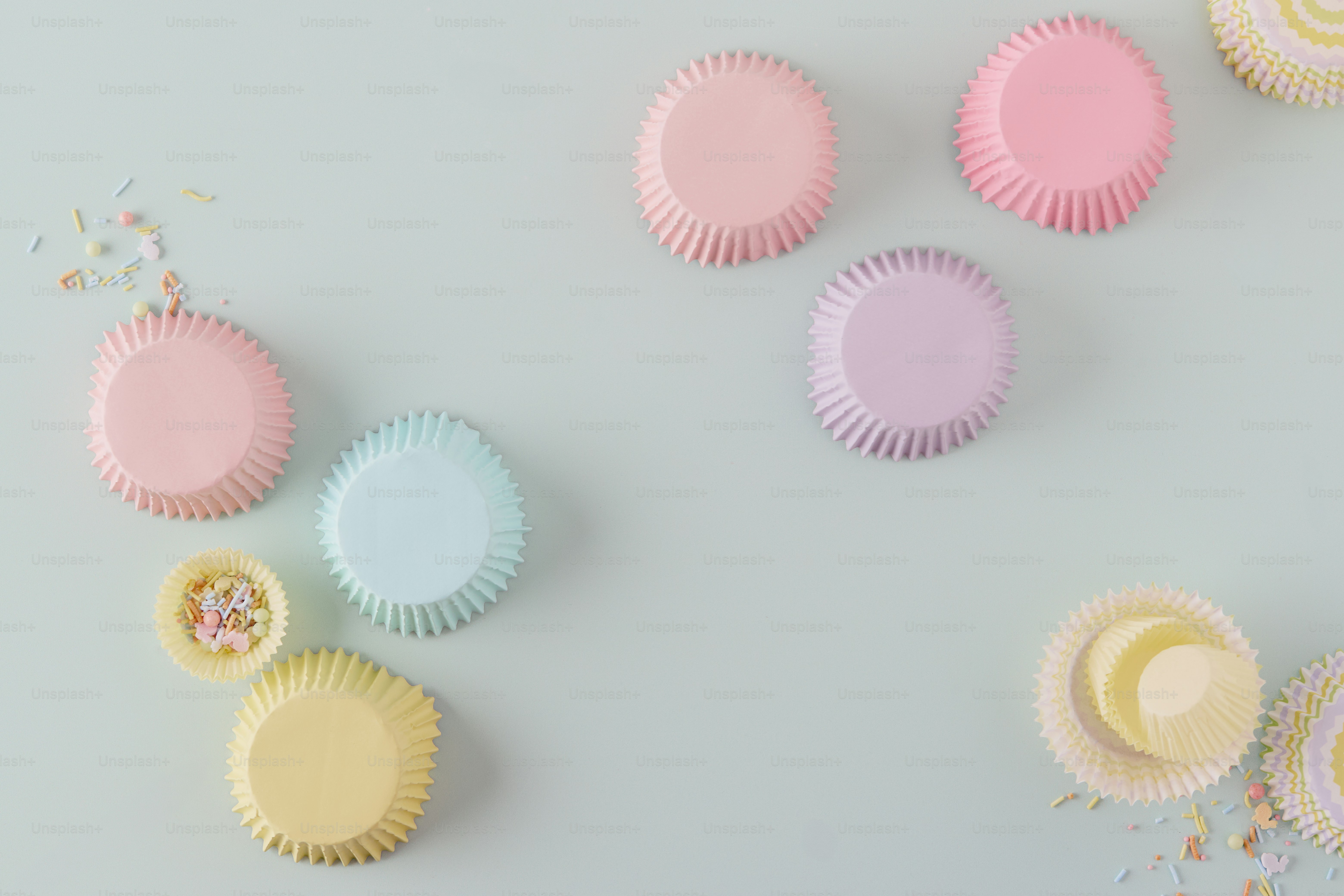 Pastel cupcake liners and sprinkles on a light blue background