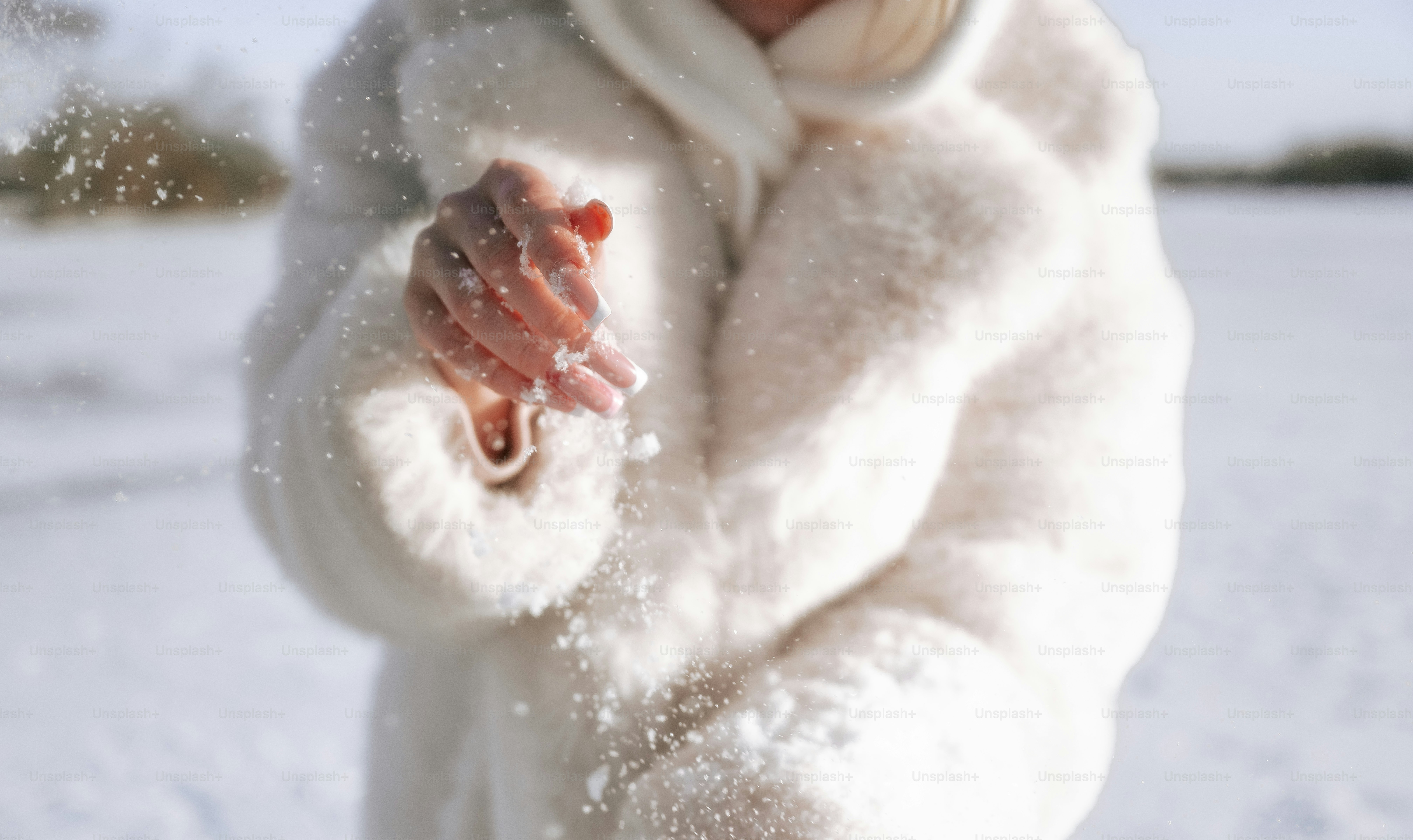 A person in a white fur coat throws snow