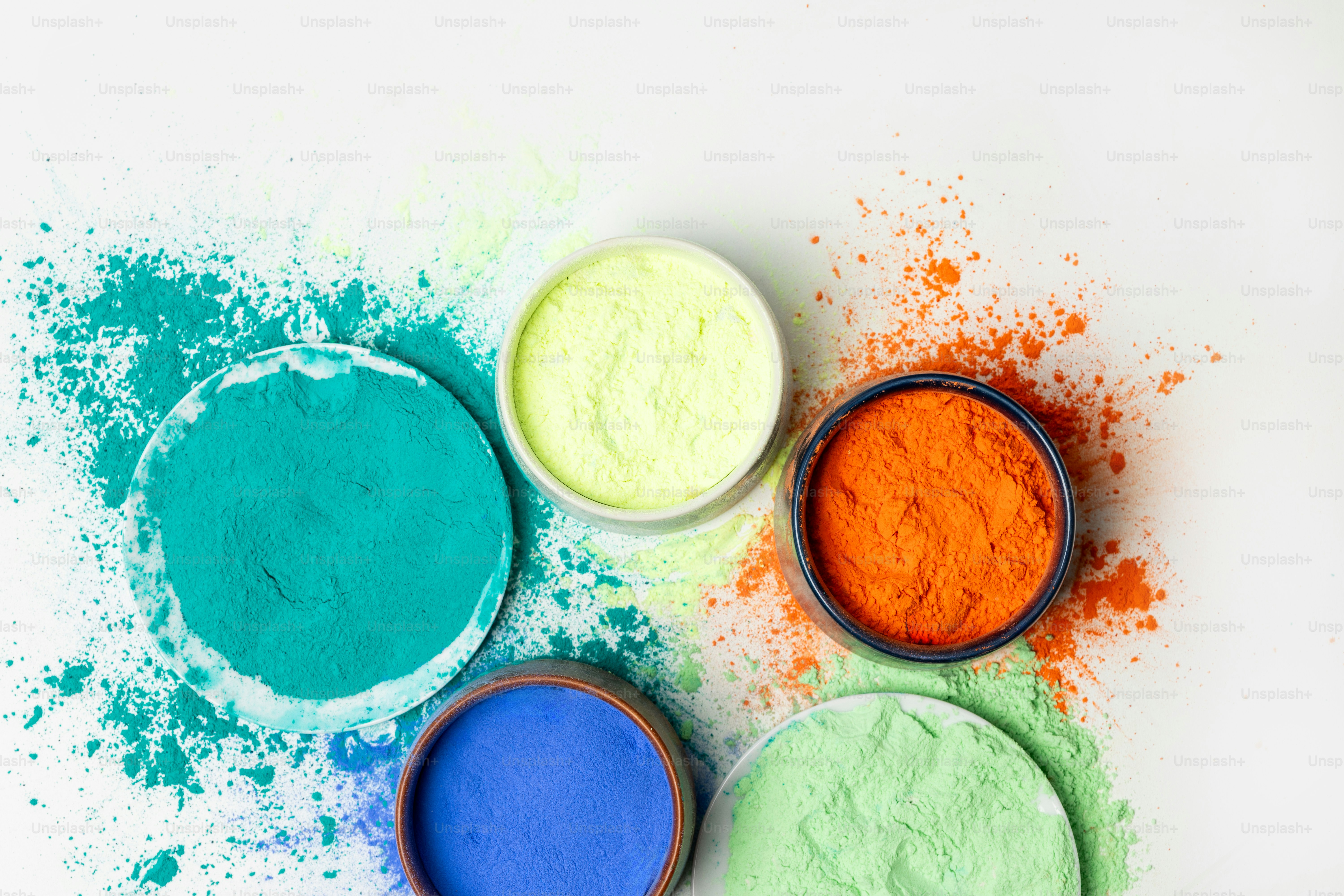 Five bowls of colorful powders on white background