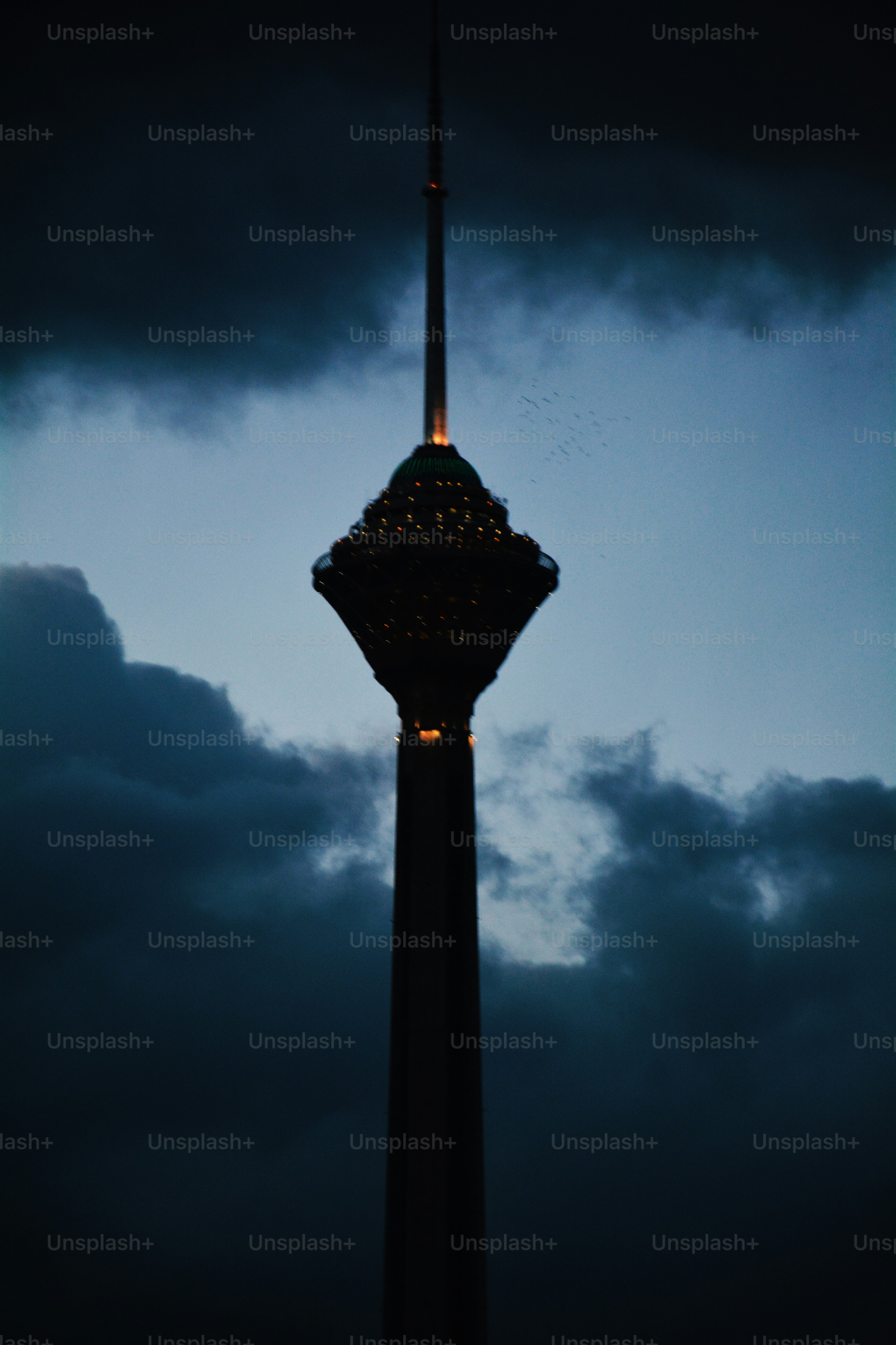 A tall tower illuminated against a dark, cloudy sky.