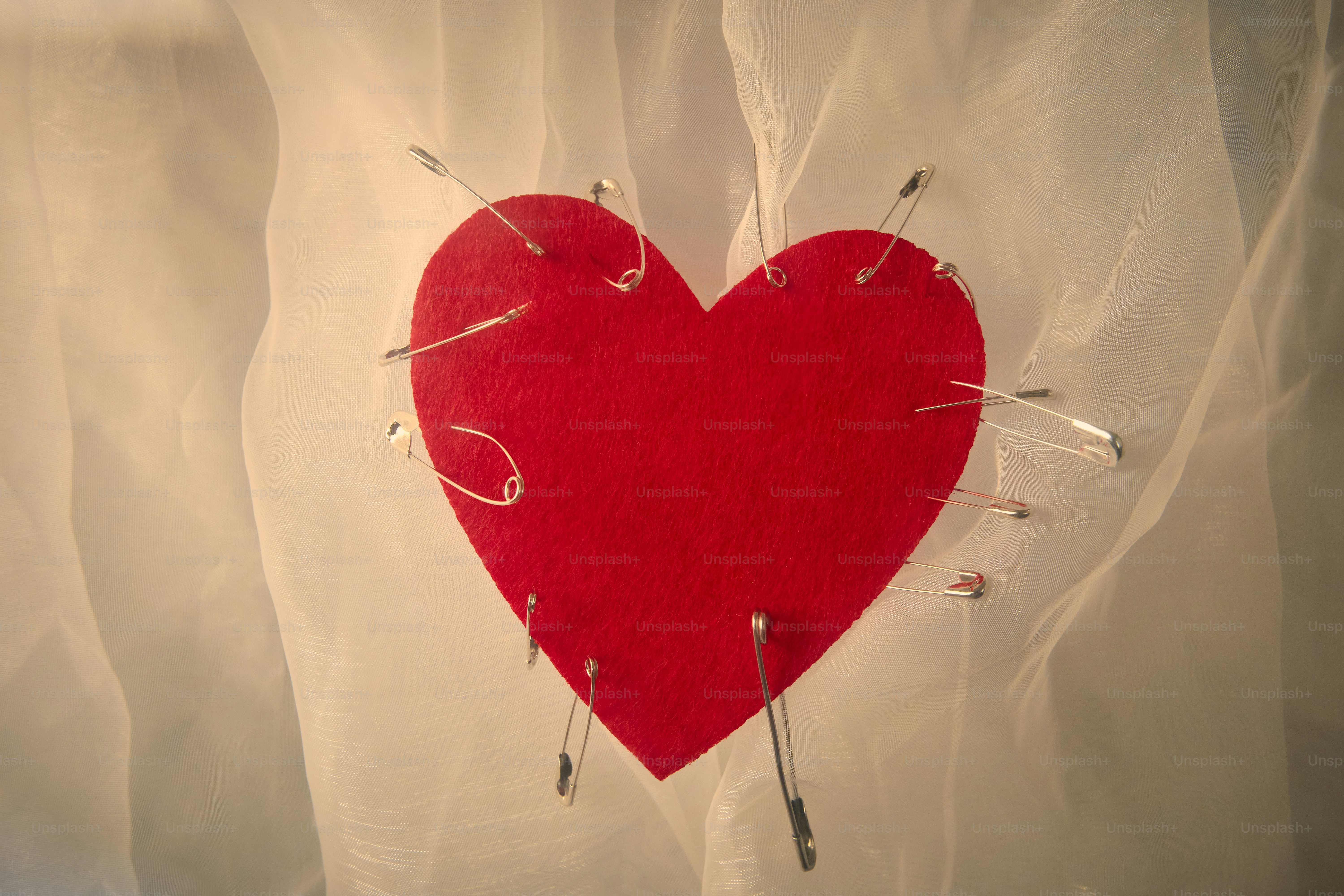 Ein rotes Herz, das auf einen durchsichtigen weißen Stoff gesteckt ist