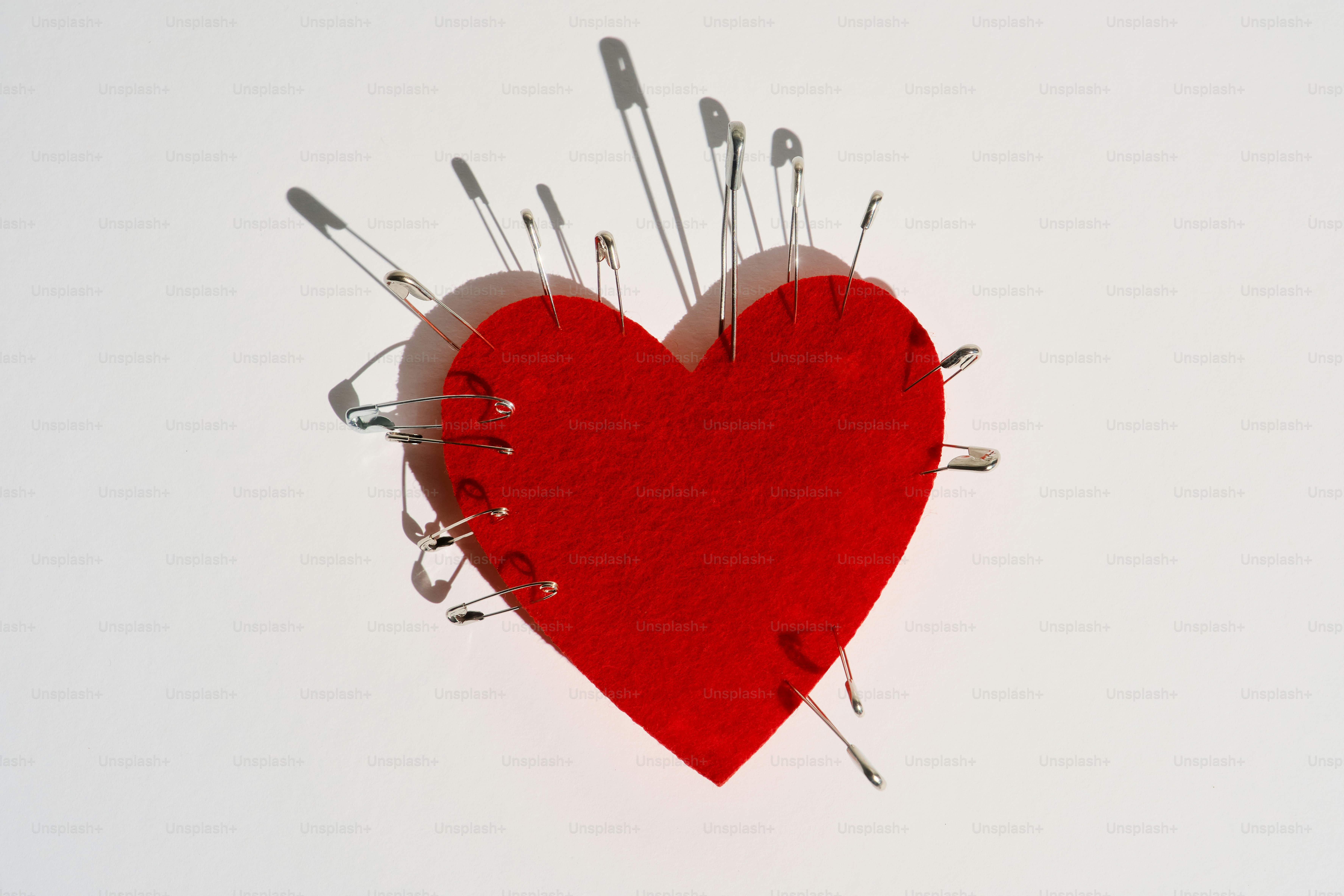 Rotes Herz, durchbohrt mit vielen Sicherheitsnadeln