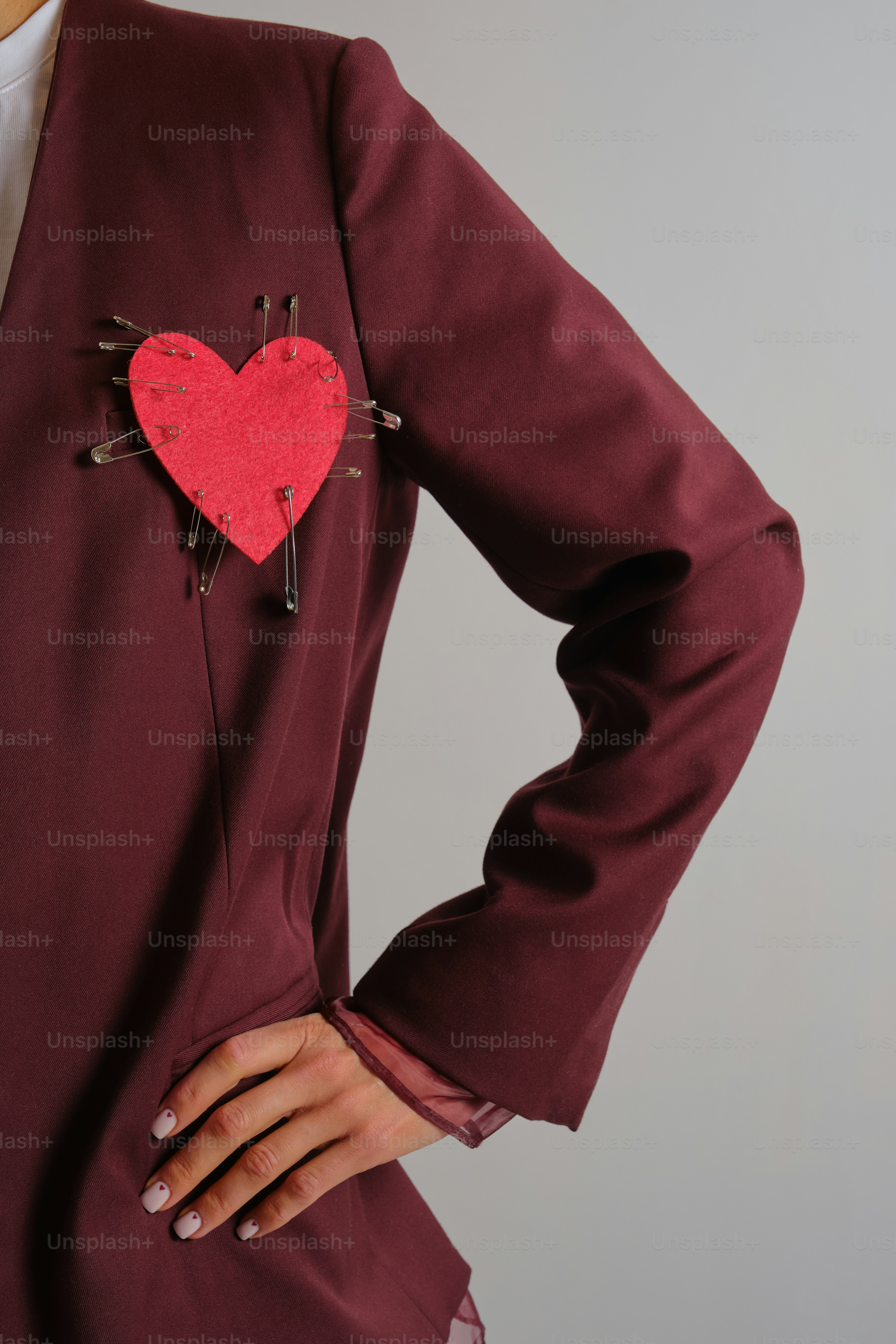 Rotes Herz mit Sicherheitsnadeln an der kastanienbraunen Jacke befestigt
