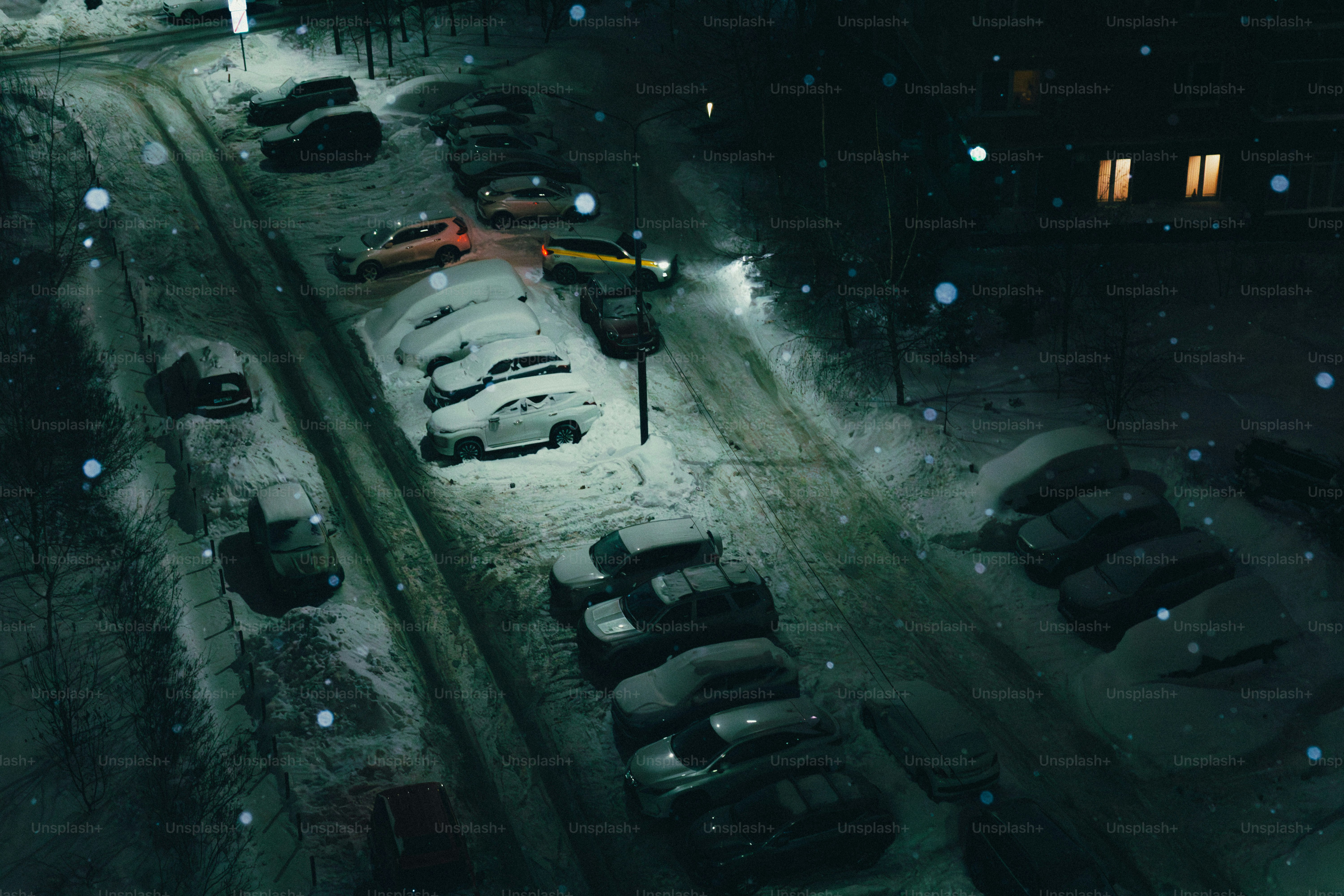 Schnee, der nachts auf einem schwach beleuchteten Parkplatz fällt.