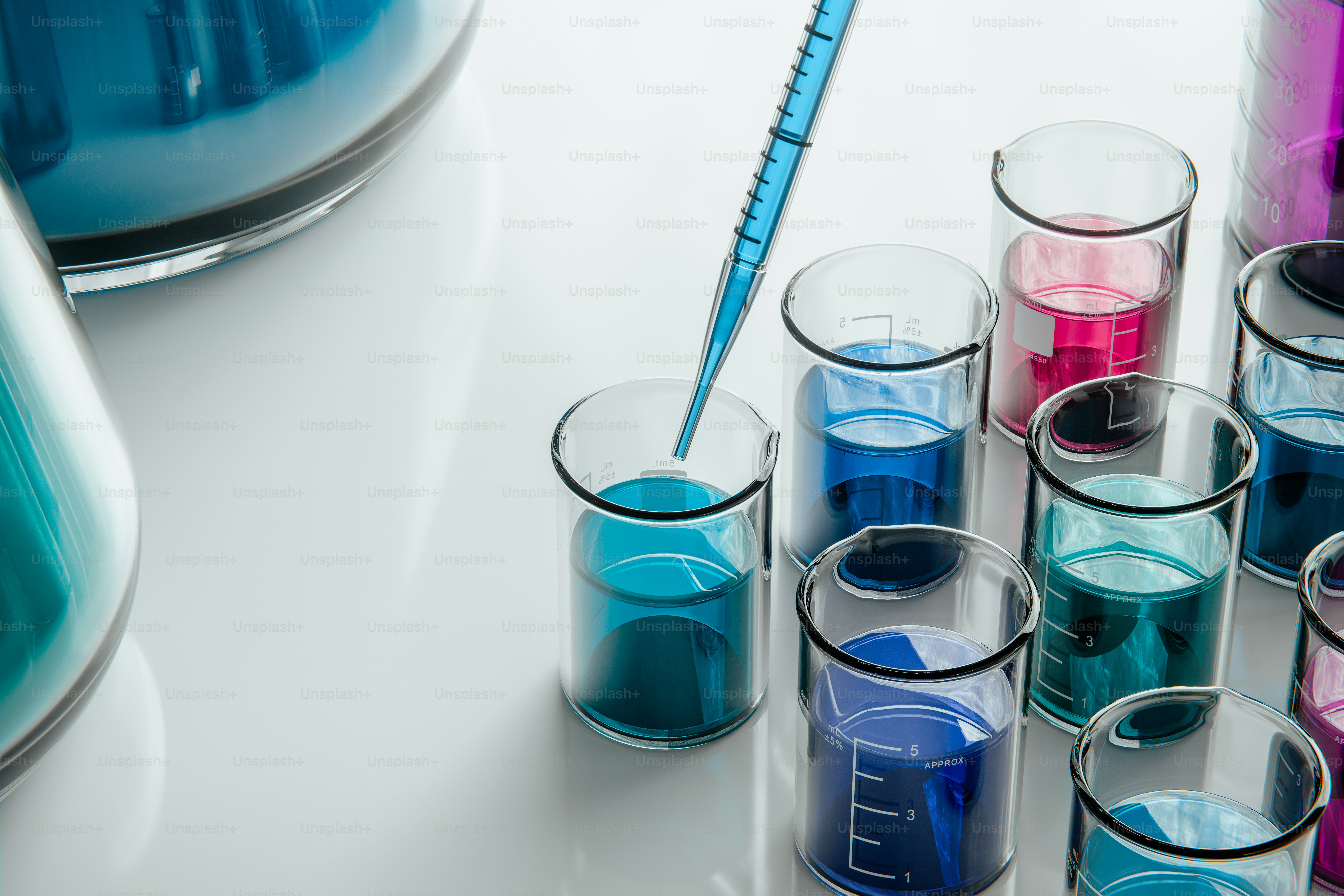 Blue pipette adding liquid to beaker with colorful solutions