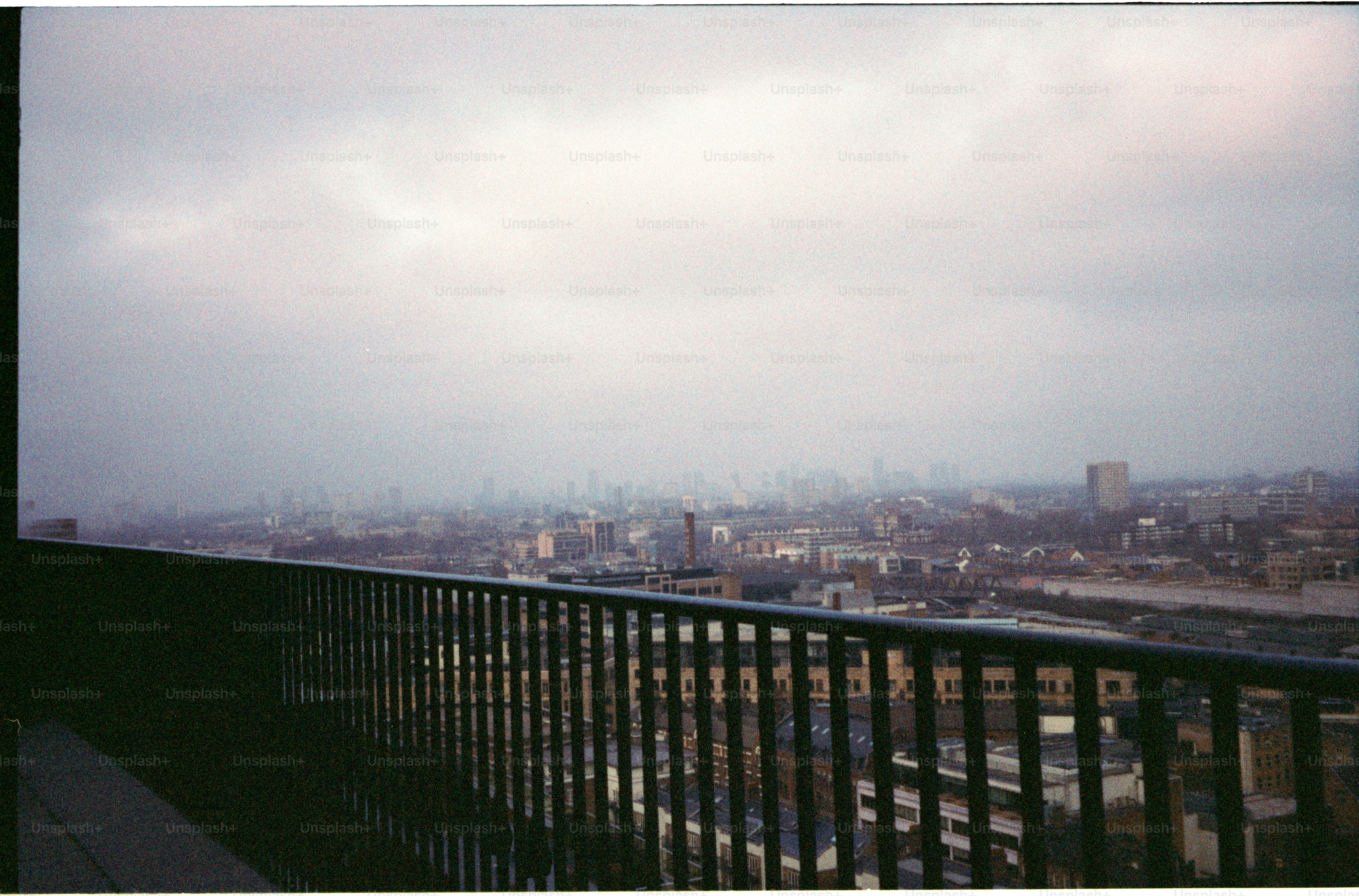 A hazy cityscape viewed from a balcony railing.