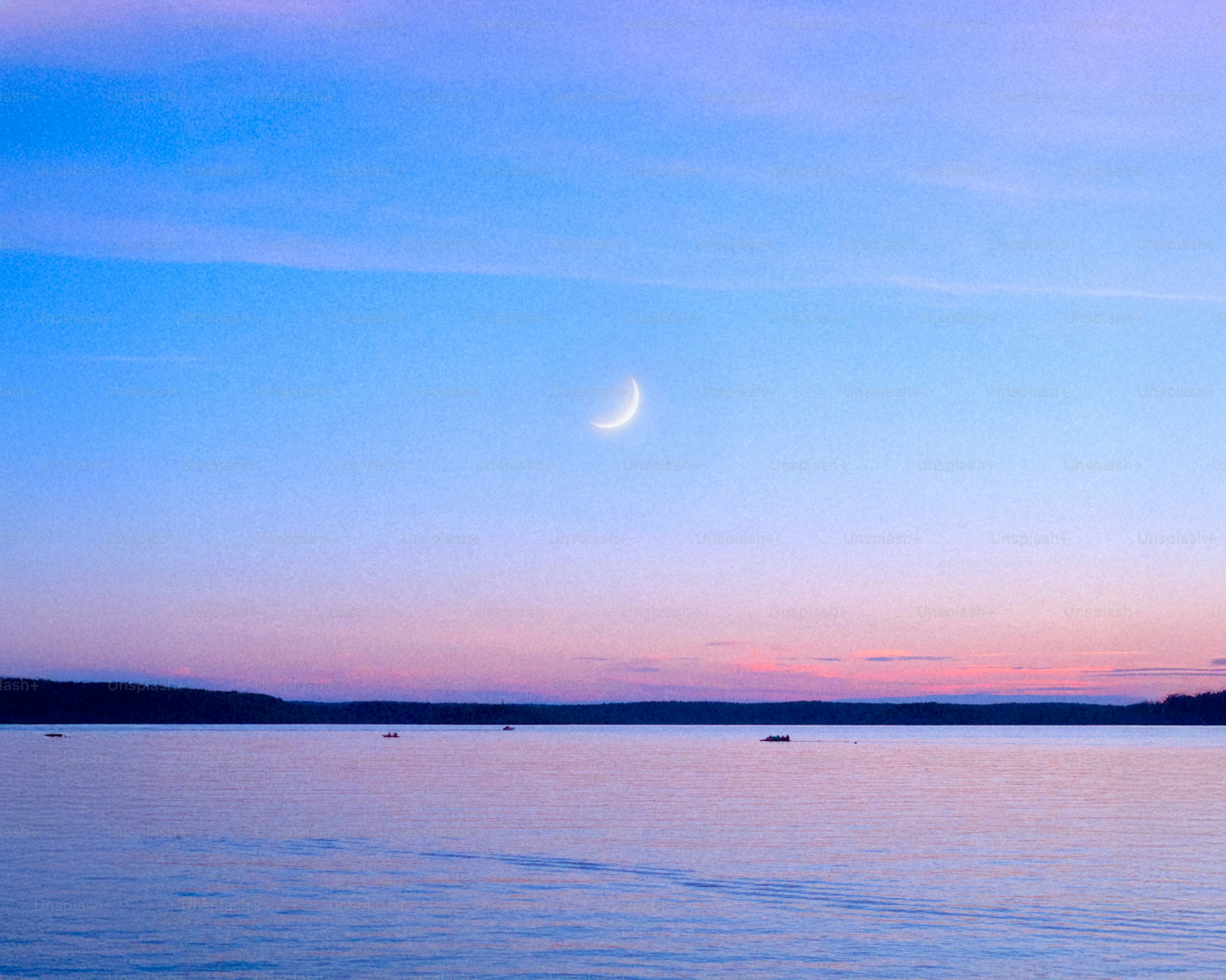 Crescent moon over a calm ocean at dusk