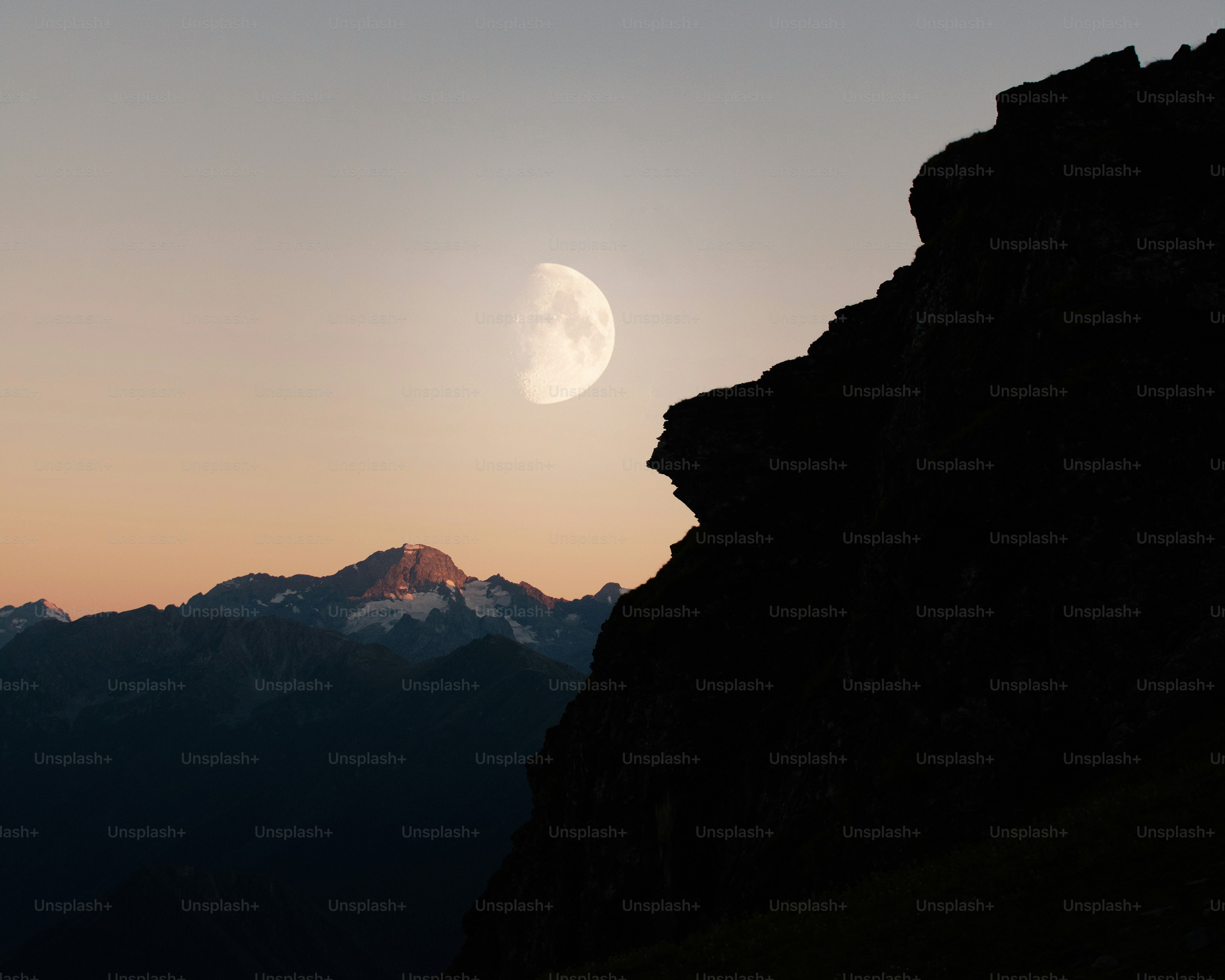 Half moon over distant mountains at dawn