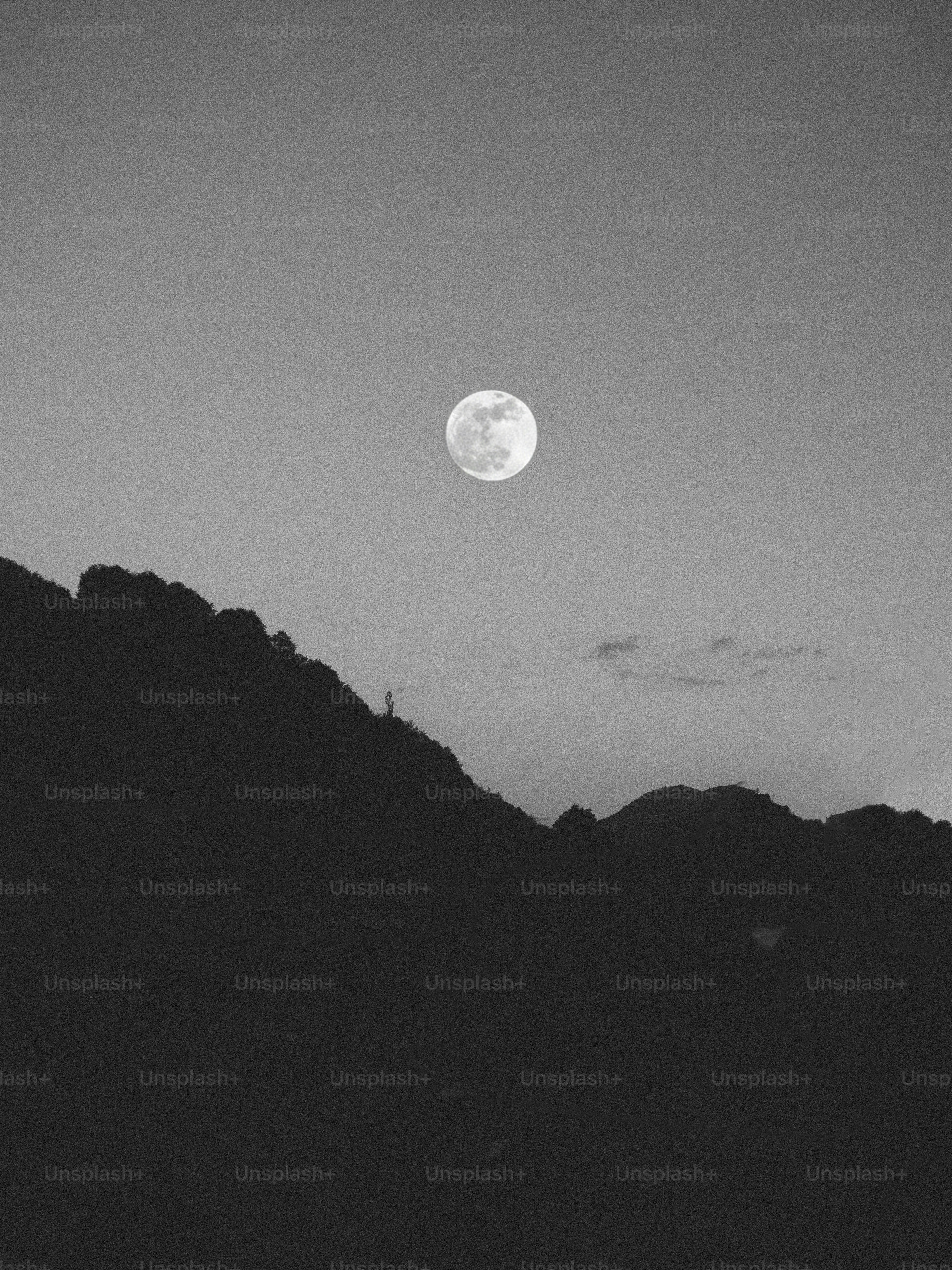 Full moon shining over silhouetted mountains at night