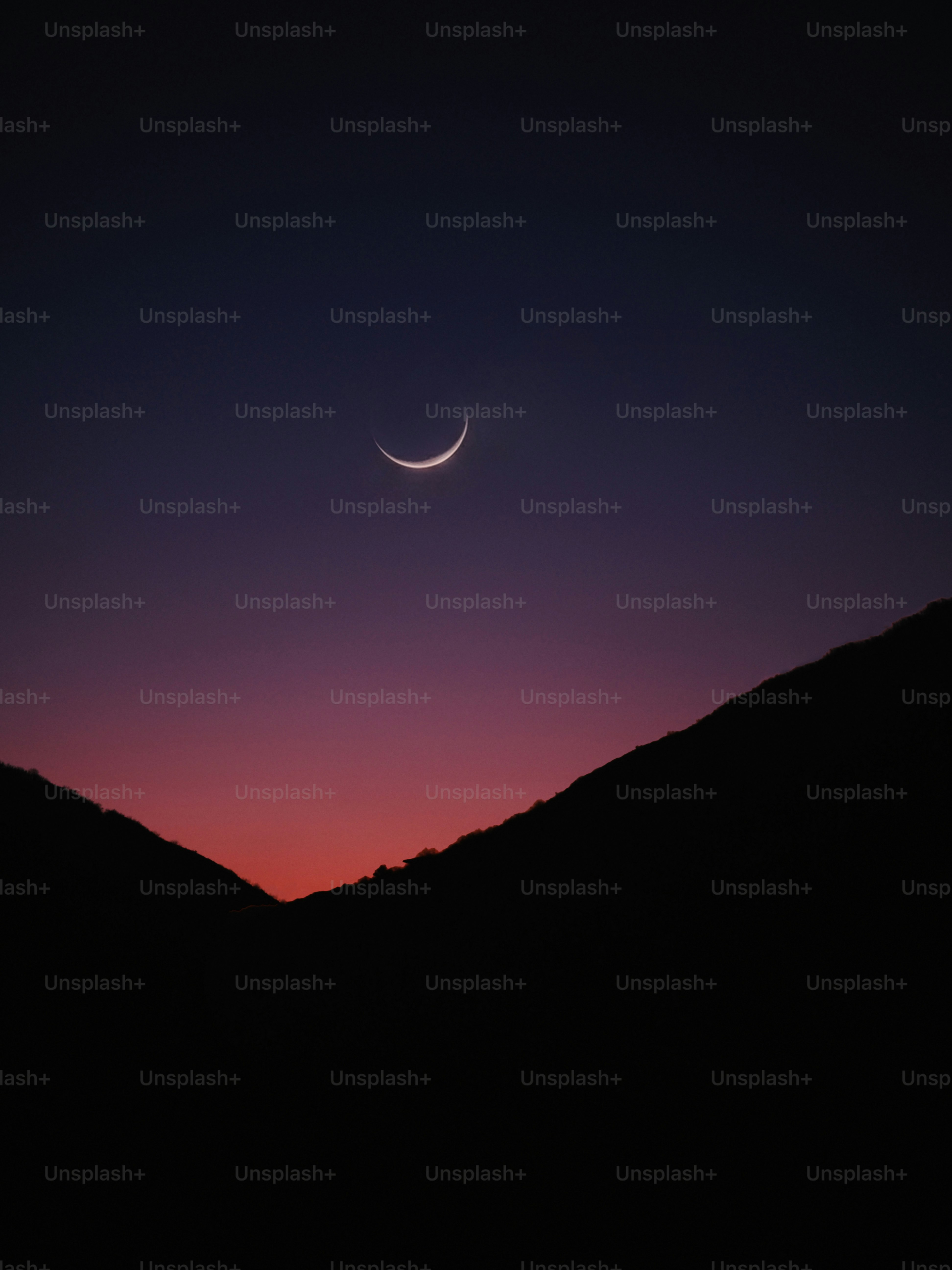 Crescent moon in a twilight sky over mountains