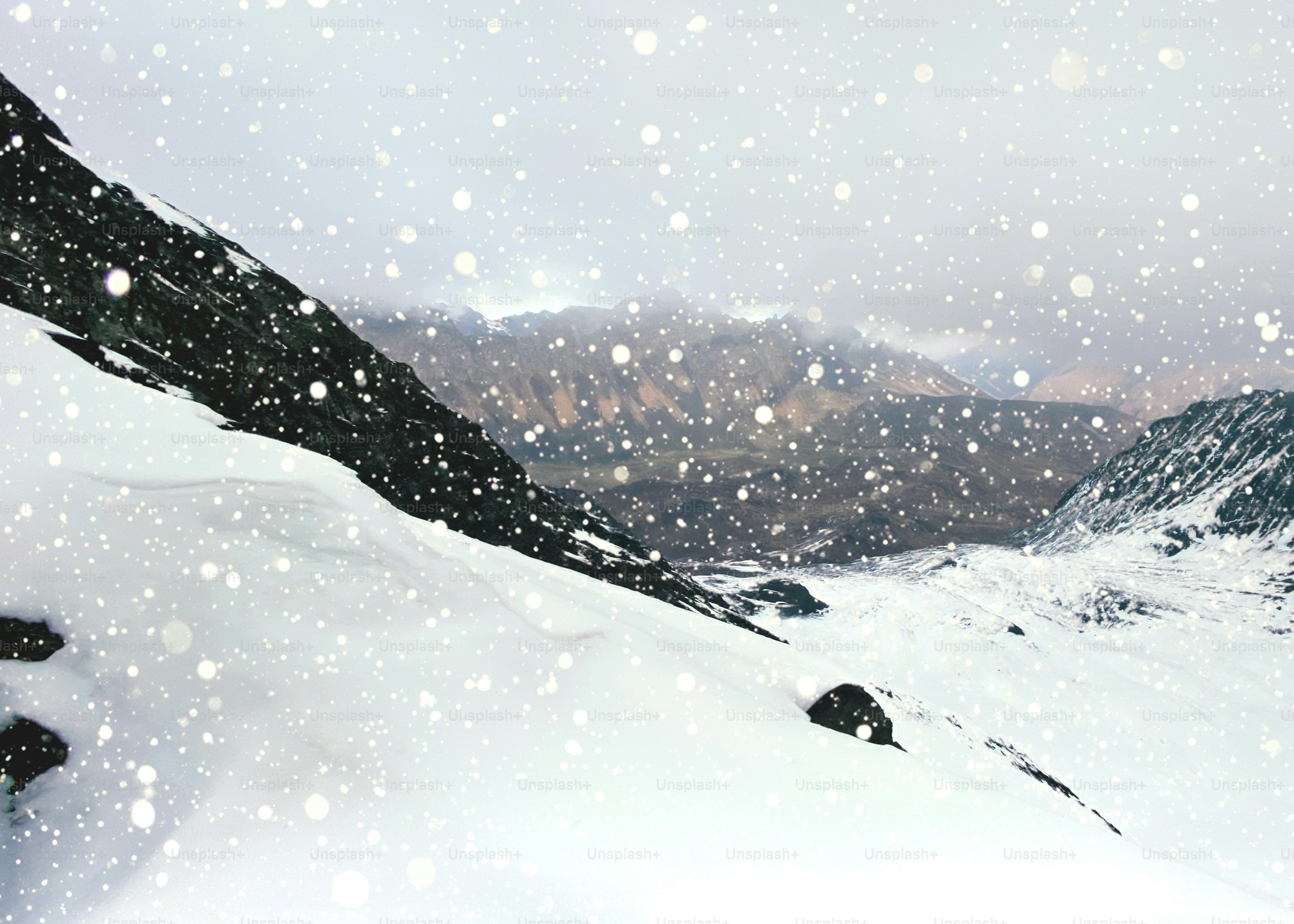Snow falling on a mountainous landscape