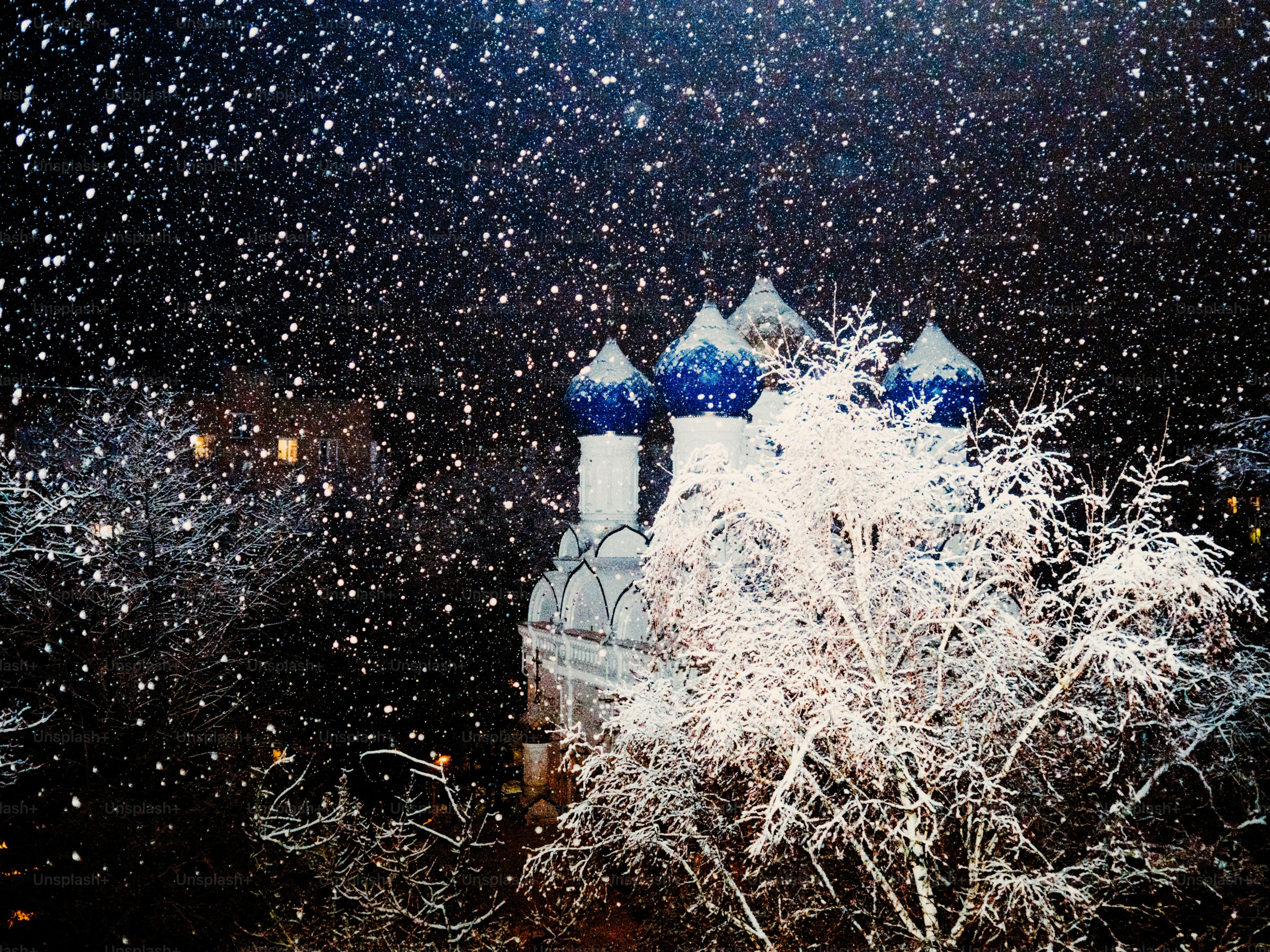Snow falling on a church with blue domes.