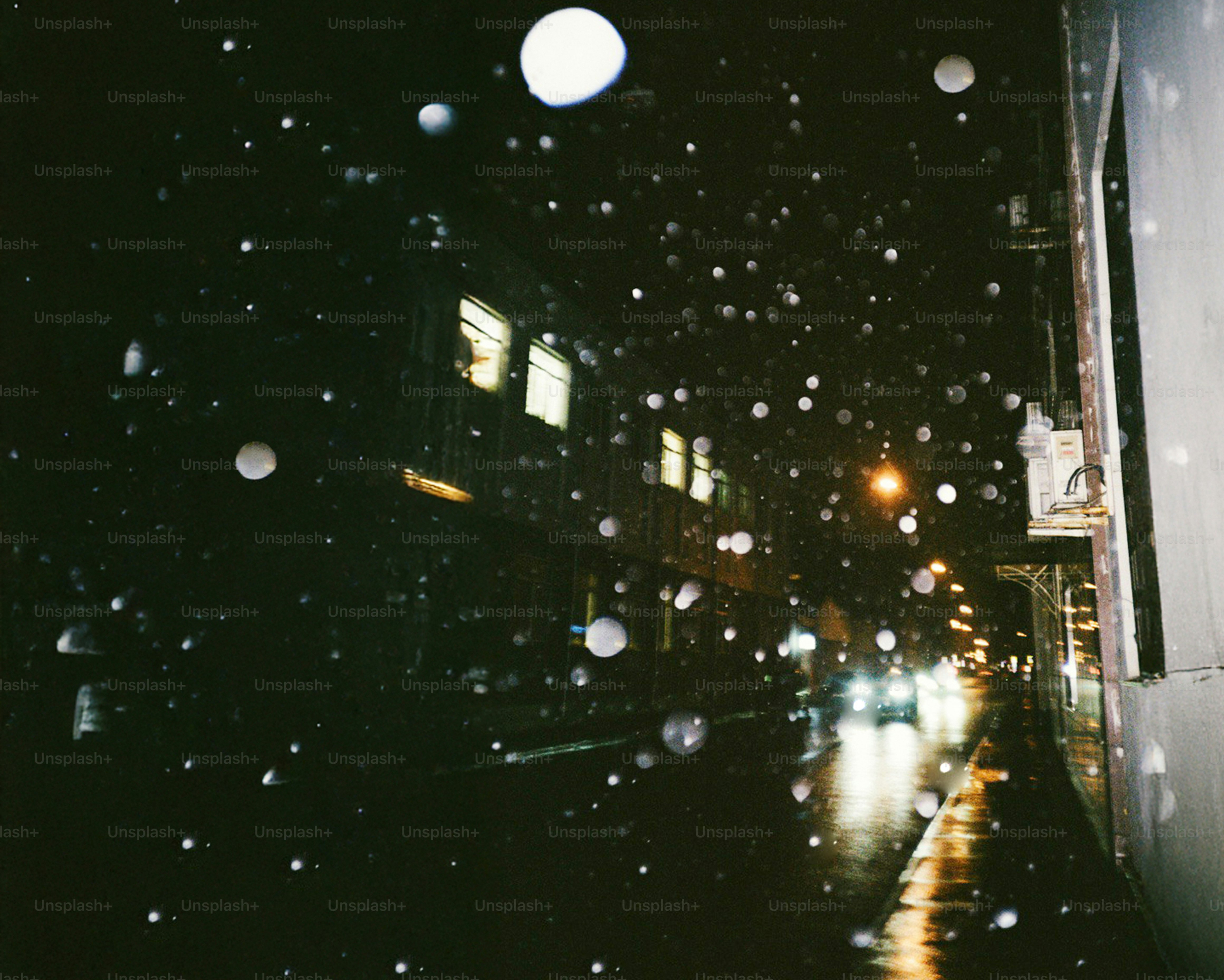 Raindrops on window overlooking a blurry city street at night.