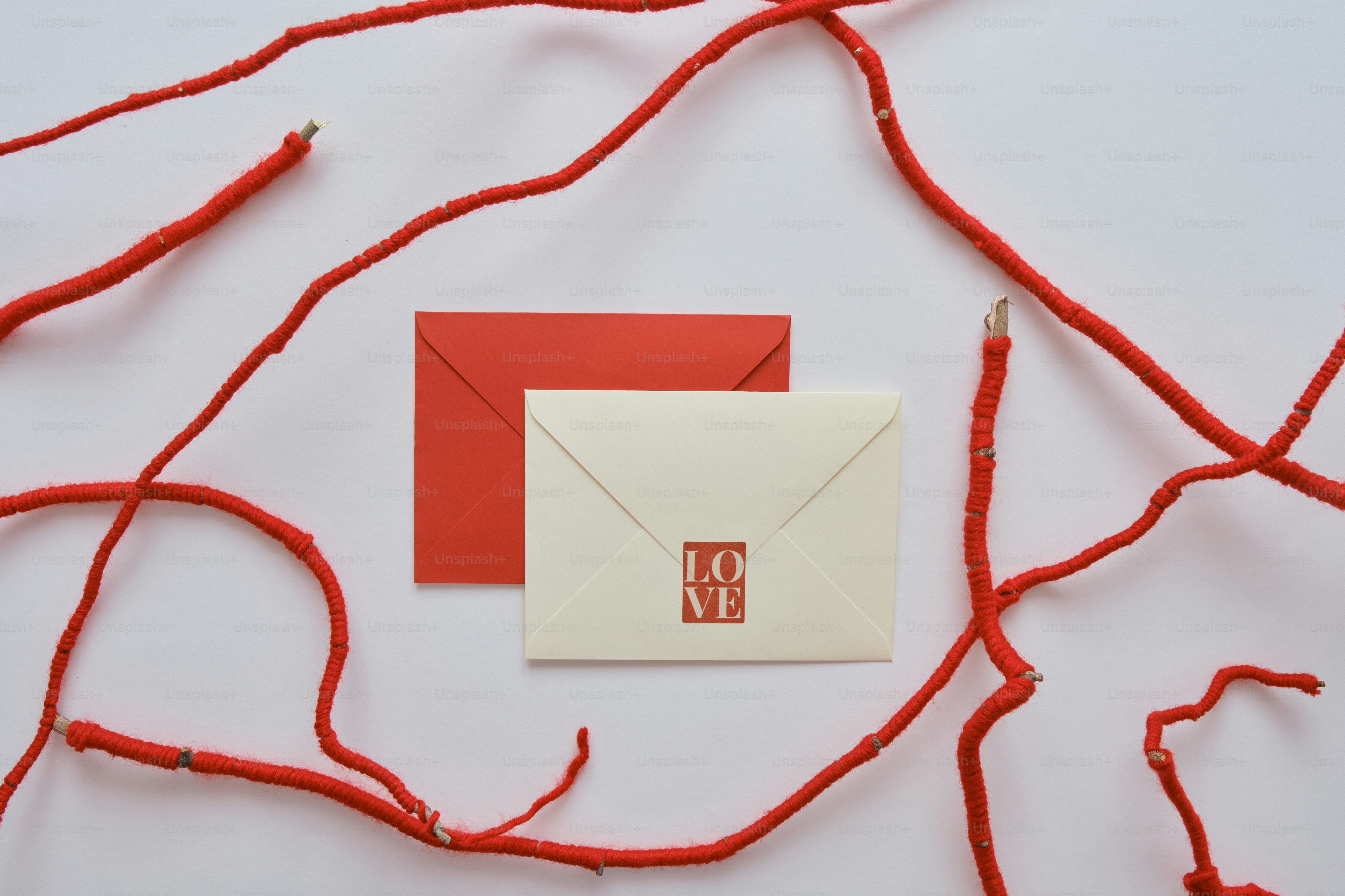 Zwei Umschläge mit roten Ästen auf weißem Hintergrund