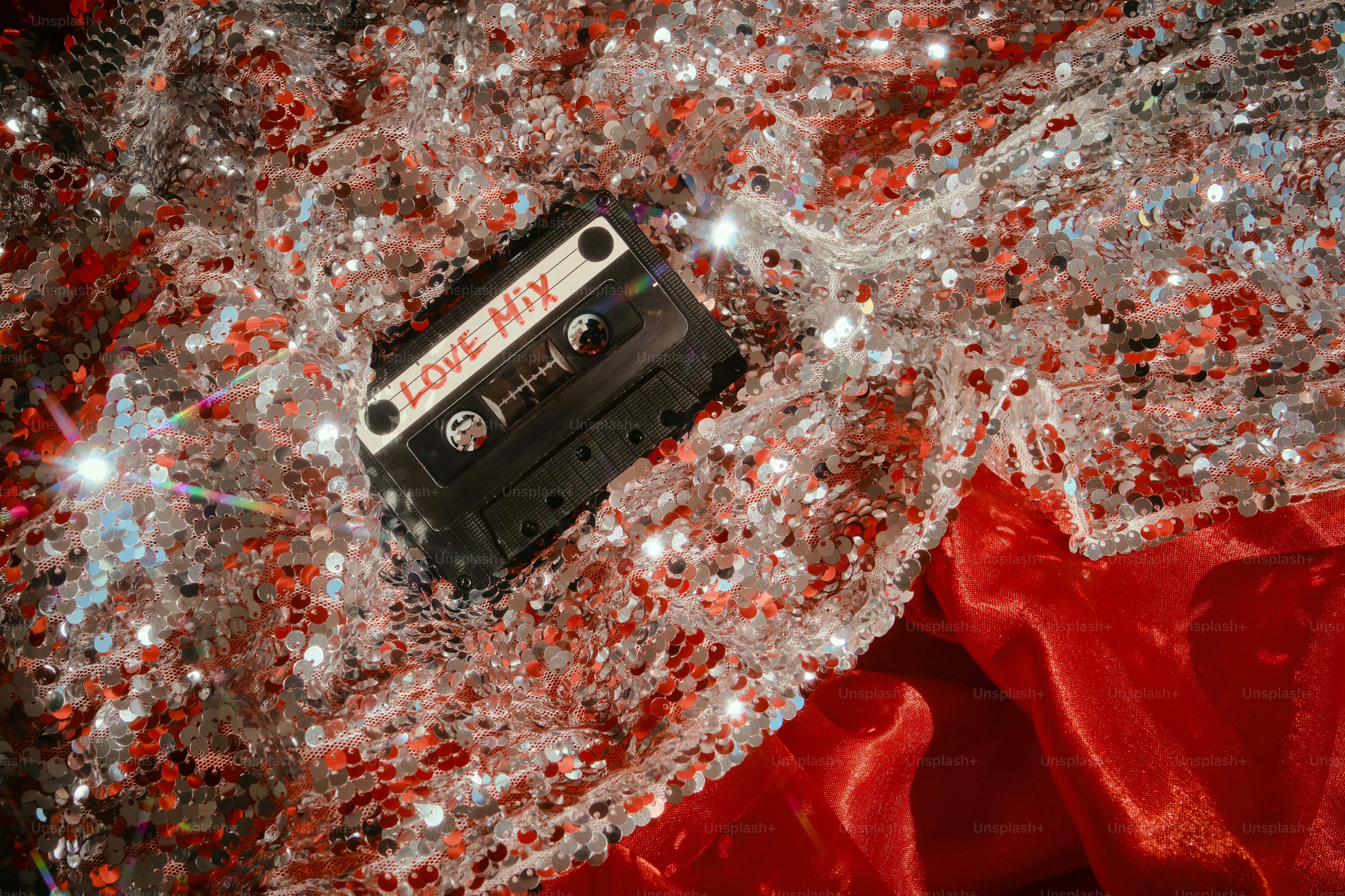 Eine Kassette mit der Aufschrift "Love Mix" auf glitzerndem Stoff.
